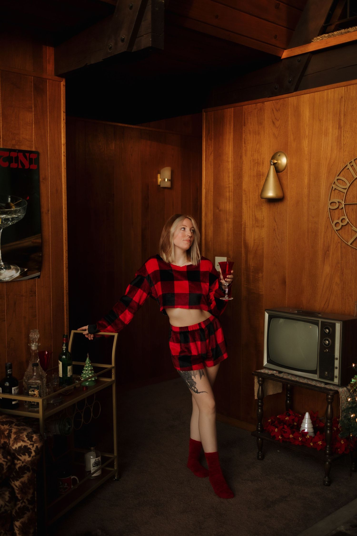 A festive holiday scene with a red and black buffalo plaid outfit in a wood-paneled room with vintage decor.