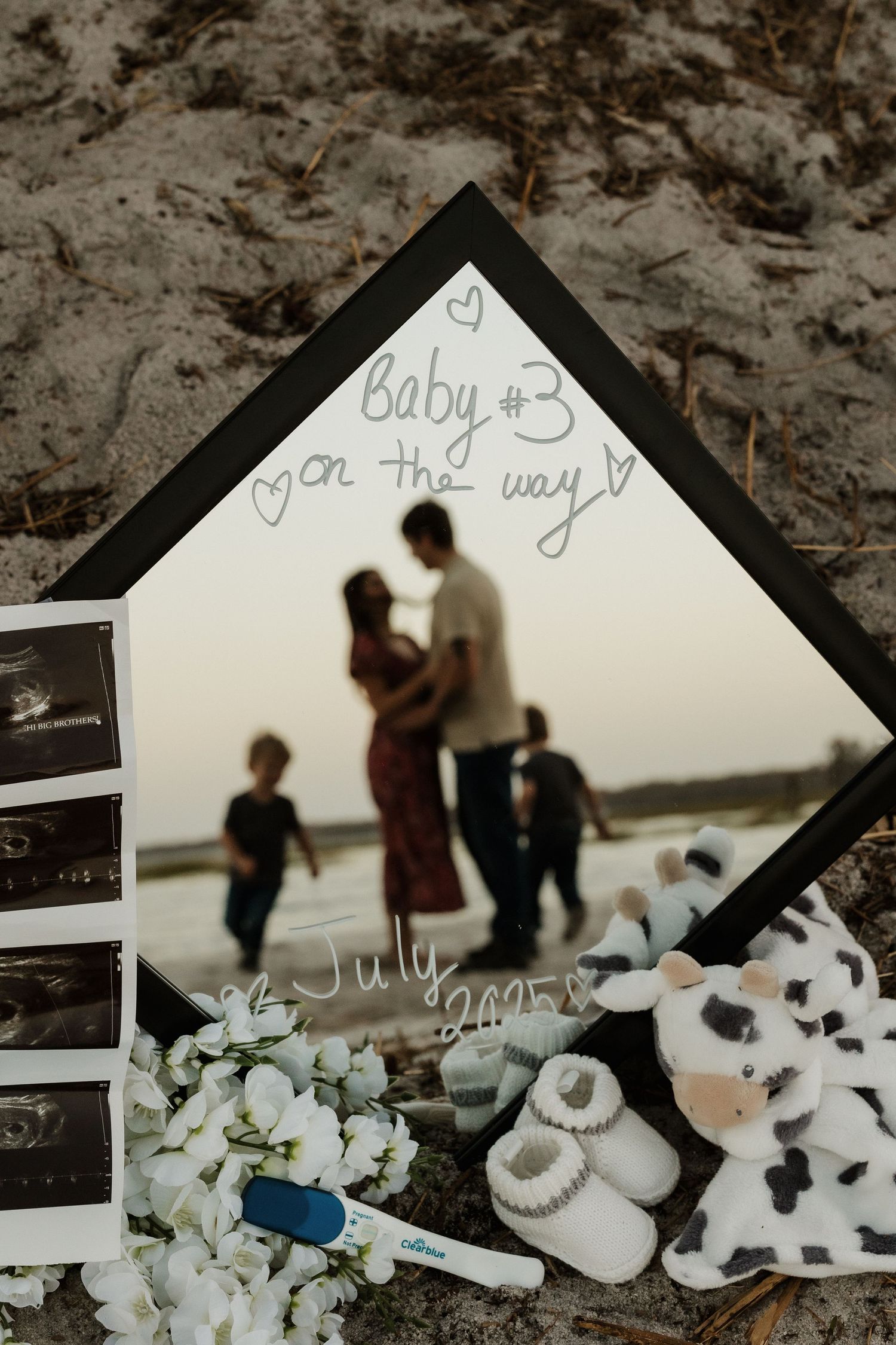 Pregnancy announcement display with ultrasound photos, baby booties, and a stuffed cow.