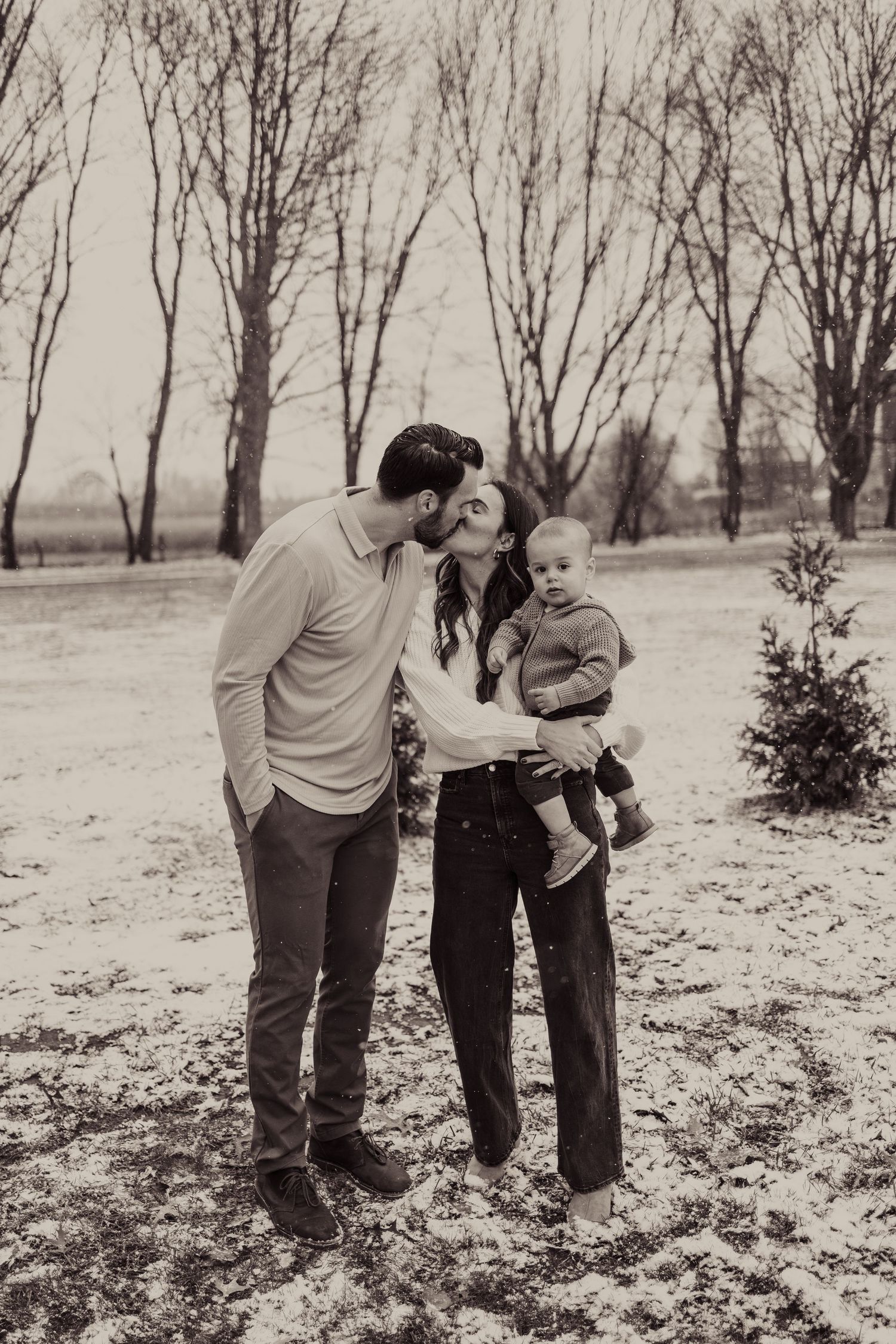 Winter family portrait in bare tree grove with black and white filter.