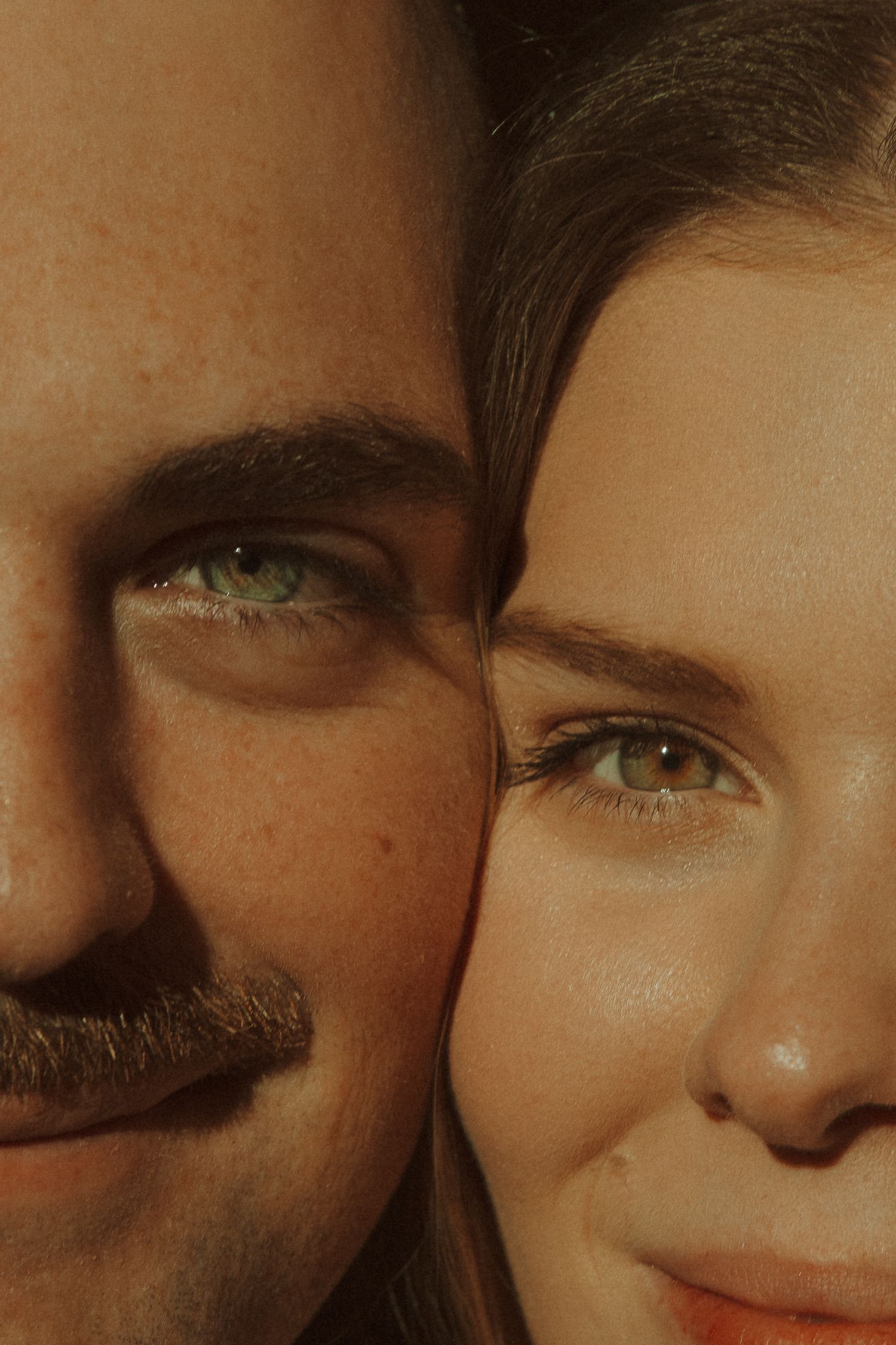Close up artistic photo showing partial faces with eyes and skin in warm lighting tones.