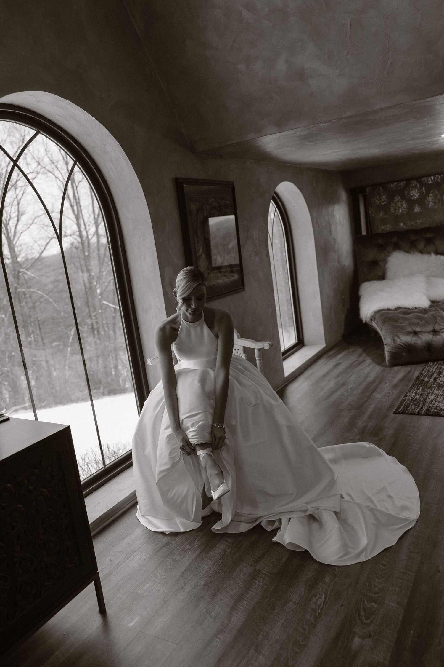 Ethereal black and white photograph showing flowing white fabric against arched windows in an empty room.