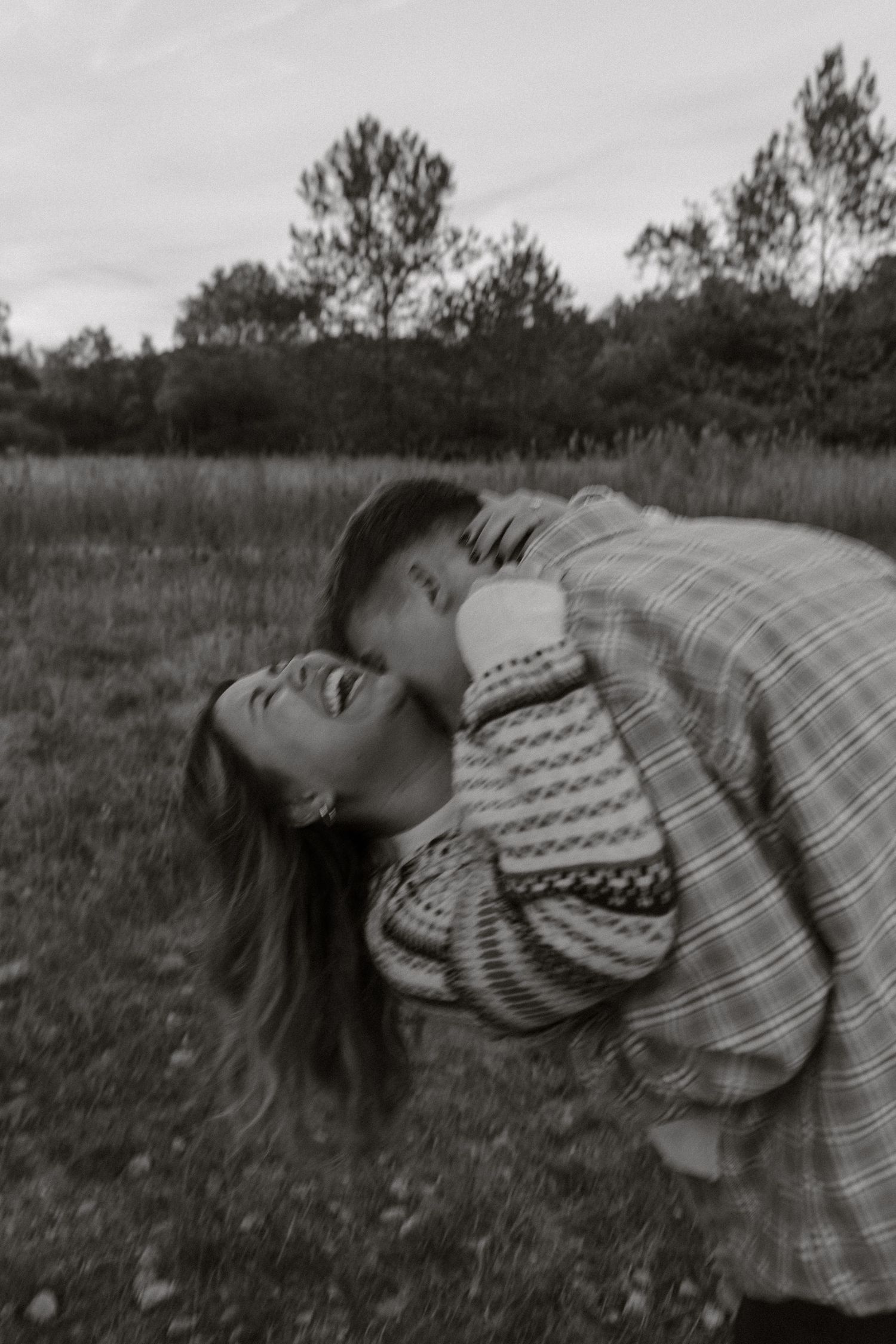 Black and white sequence of someone laying back and laughing joyfully in a grassy field.