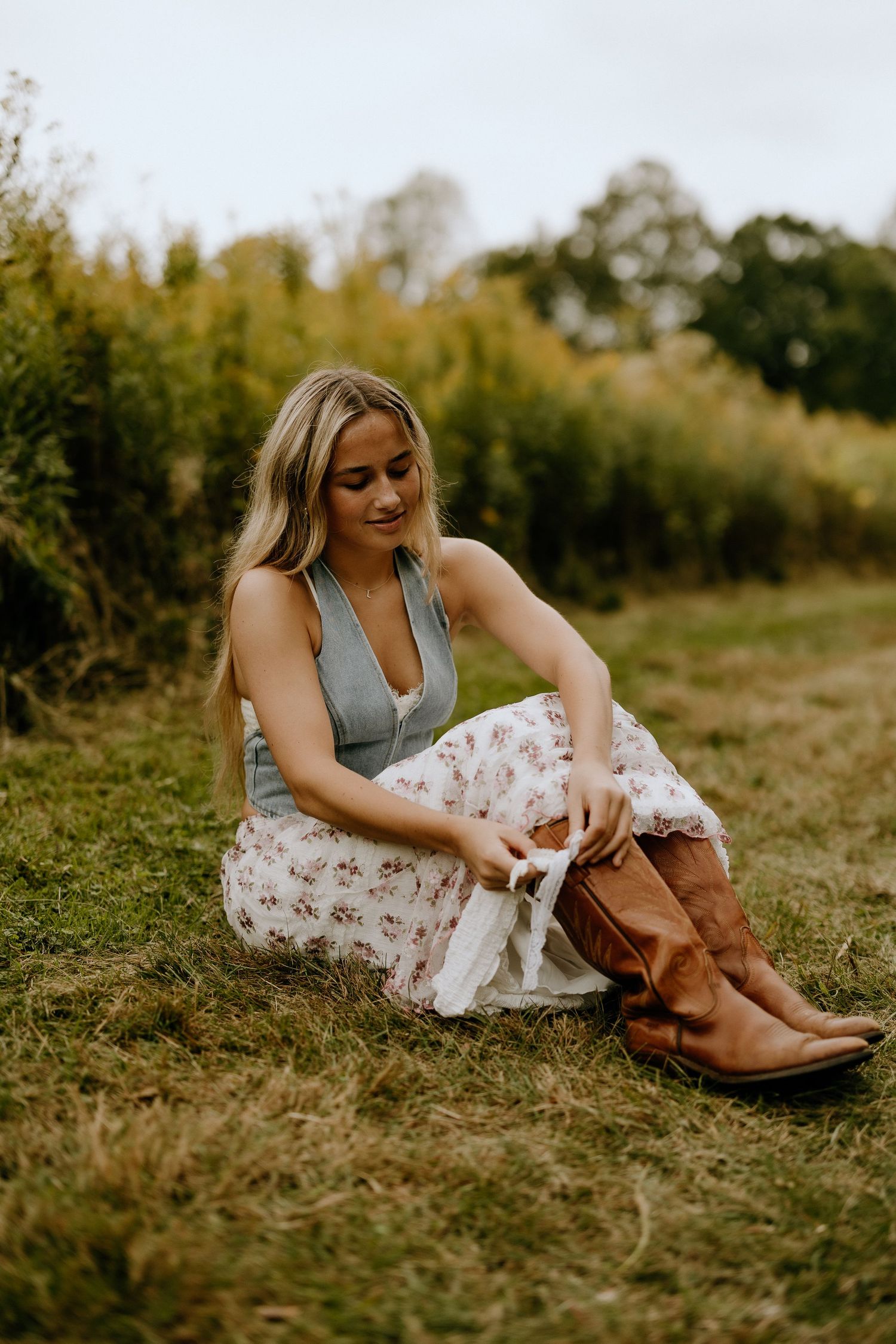 Rustic outdoor portrait showing brown boots and floral dress in autumn field.
