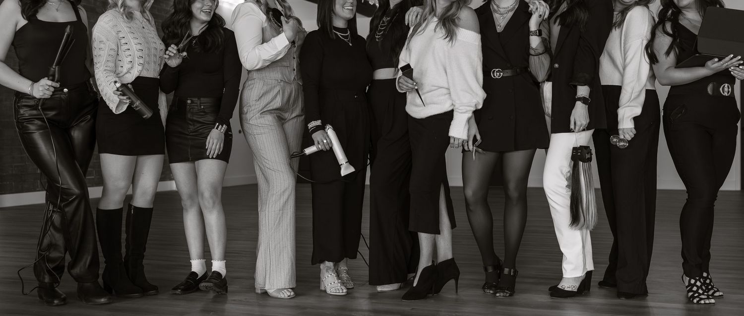 Black and white photo showing a line of people posing in fashionable outfits.