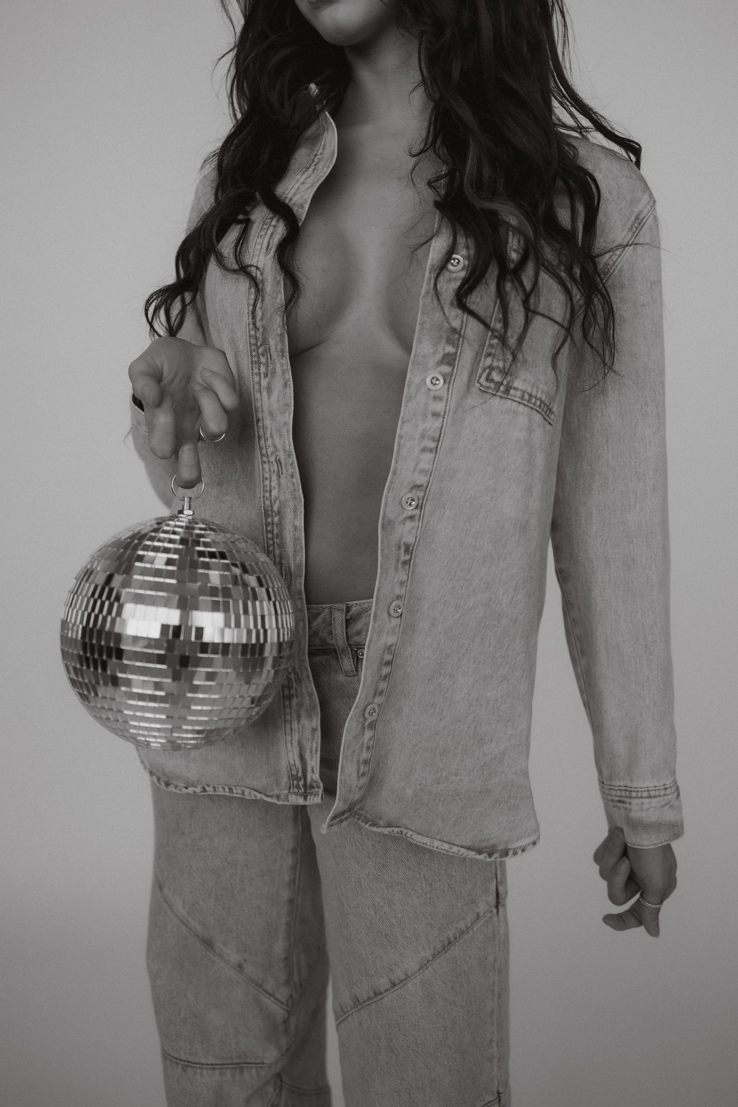 Artistic black and white photo of someone in denim holding a disco ball.