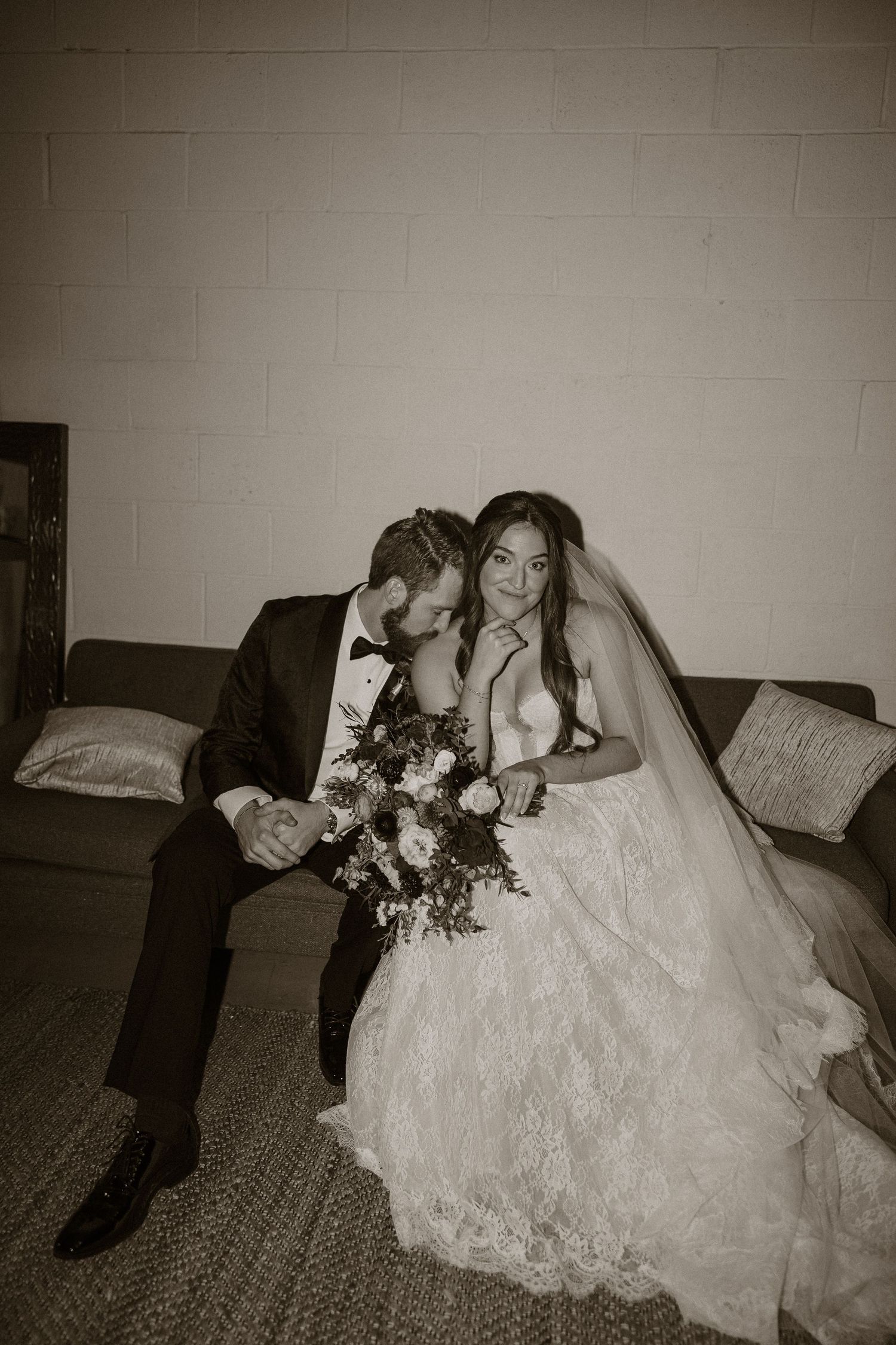 Black and white wedding photos showing intimate moments on a couch with elegant lace dress details.