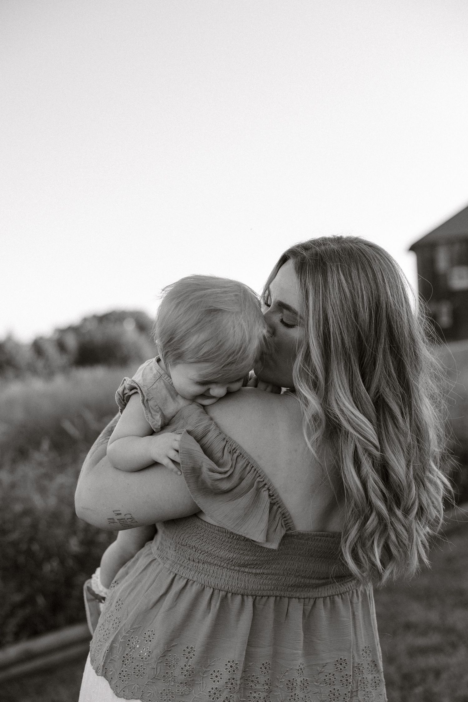 Black and white photo series showing tender moments between mother and child in an outdoor setting.