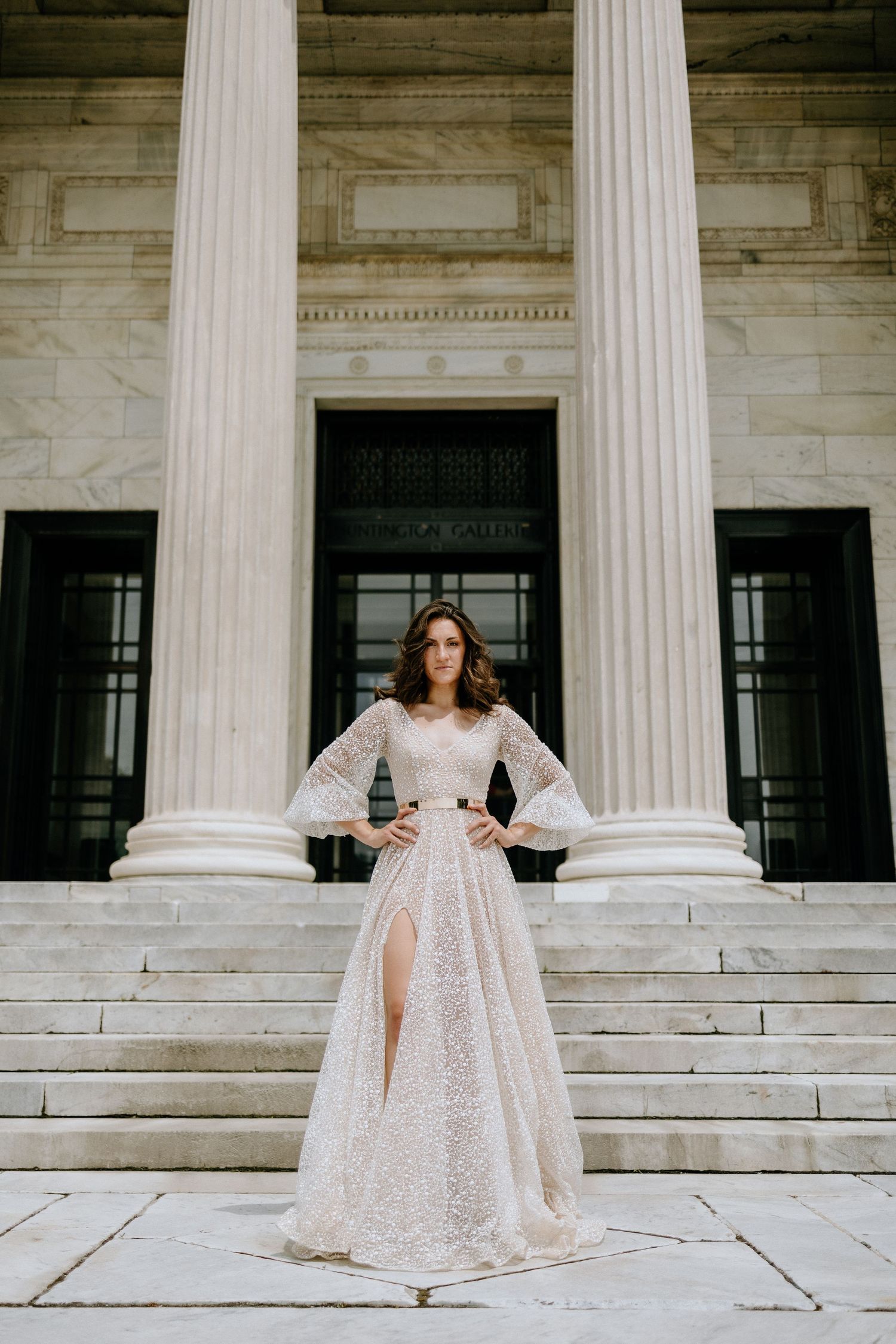 A flowing white gown creates elegance against classical marble columns.