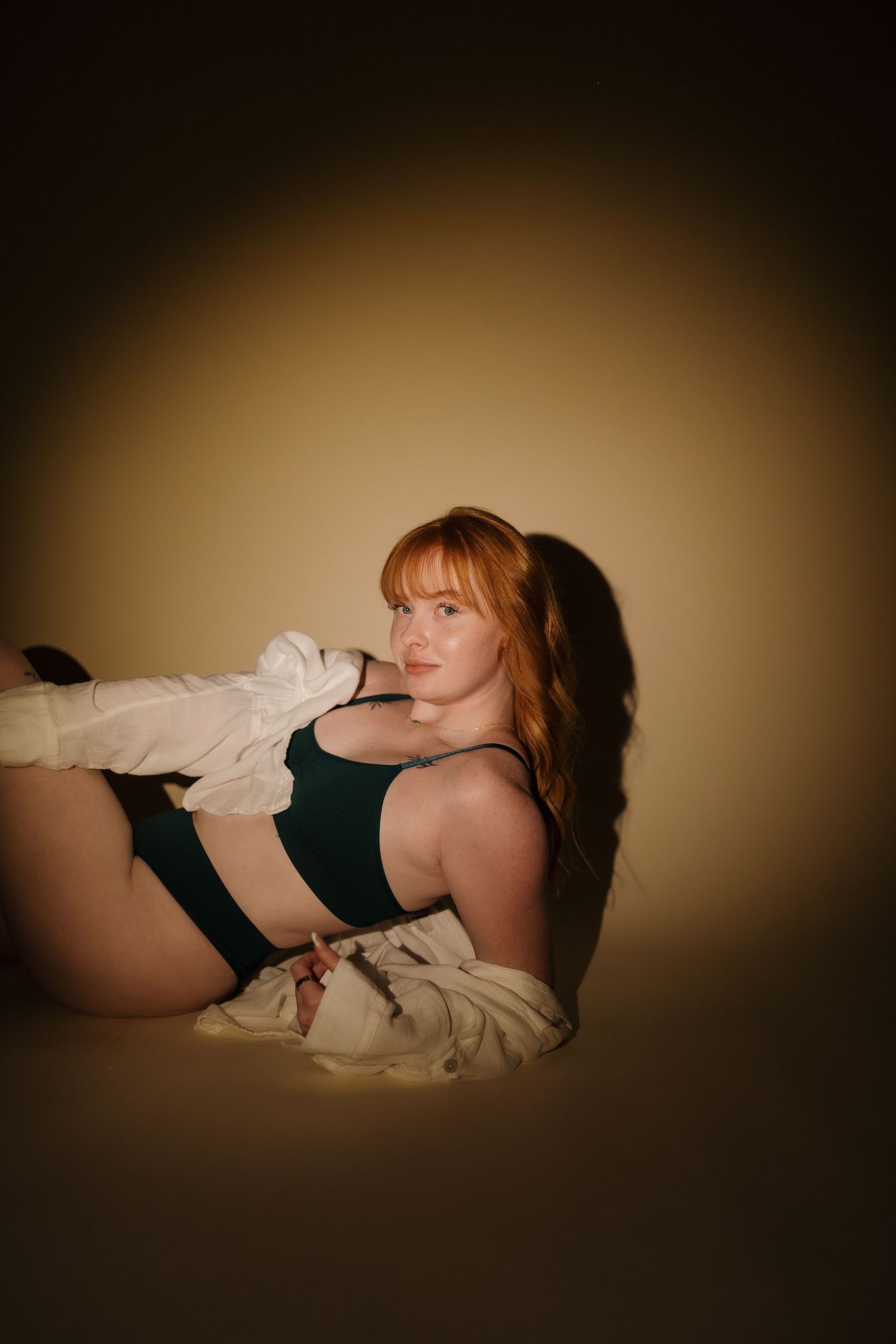 Artistic portrait in moody lighting against warm brown background.
