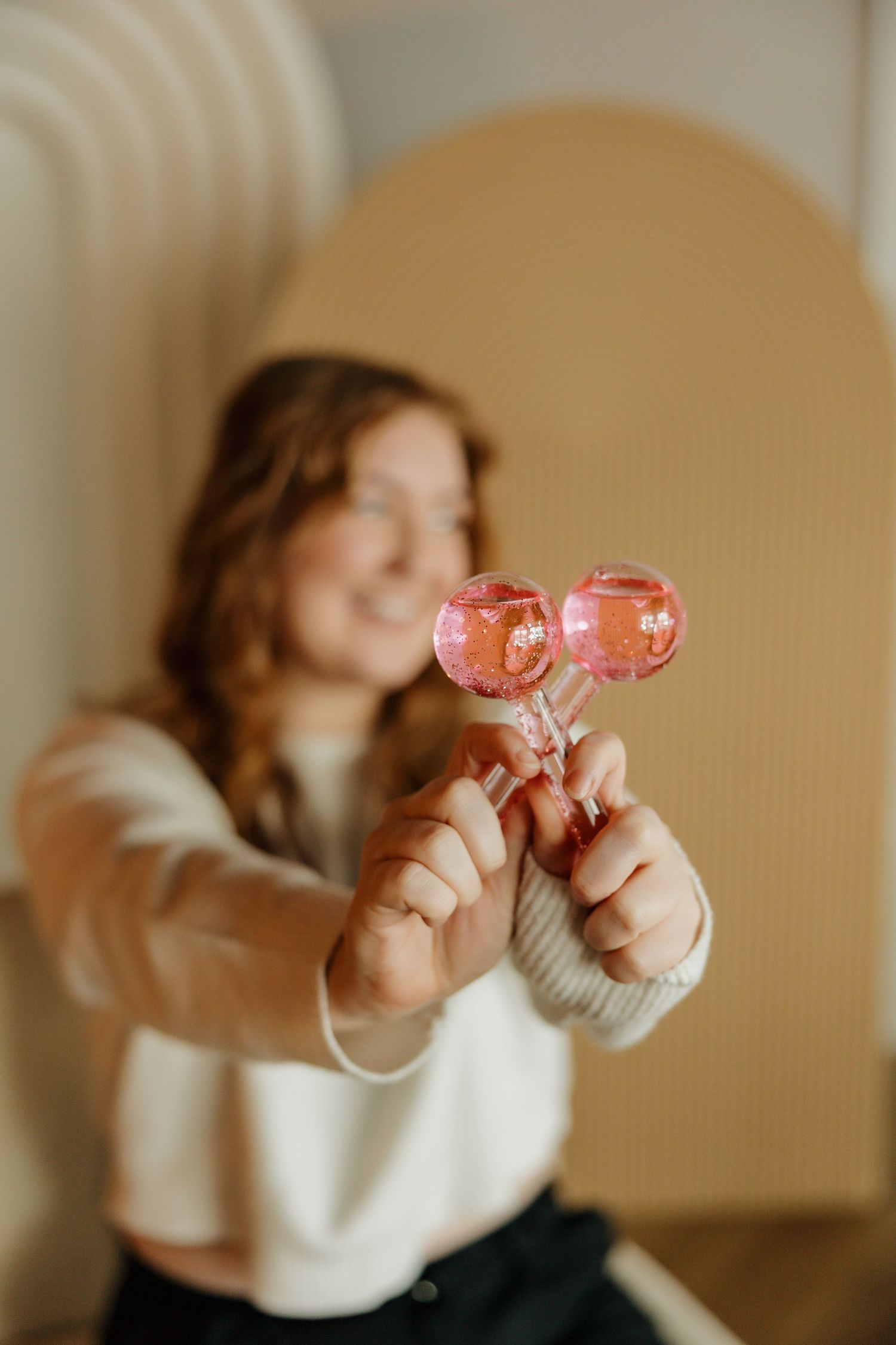 Creative shot holding pink lollipops with warm lighting and modern architectural background.