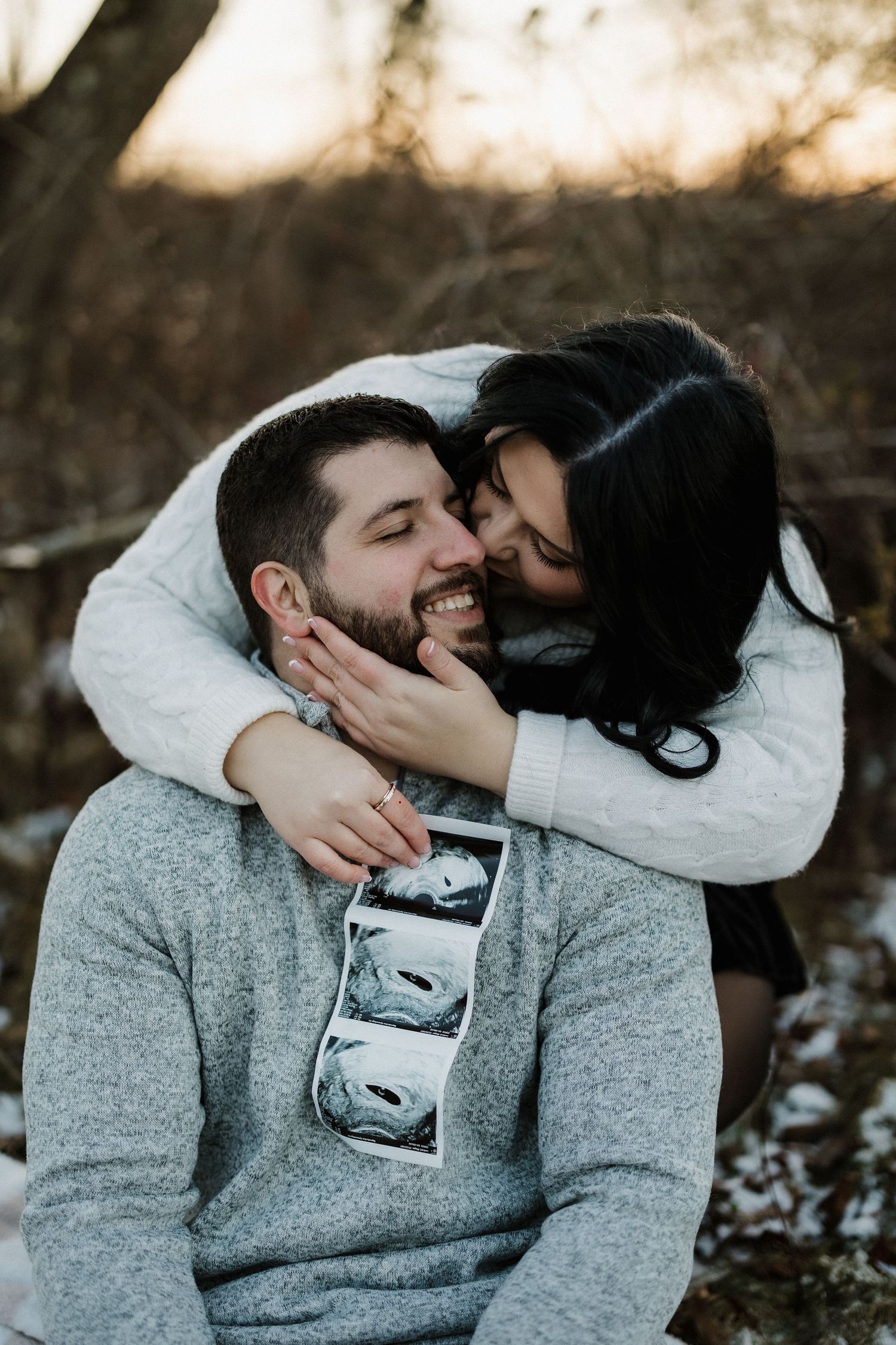 Cozy winter couple sharing intimate moment while holding ultrasound strip.