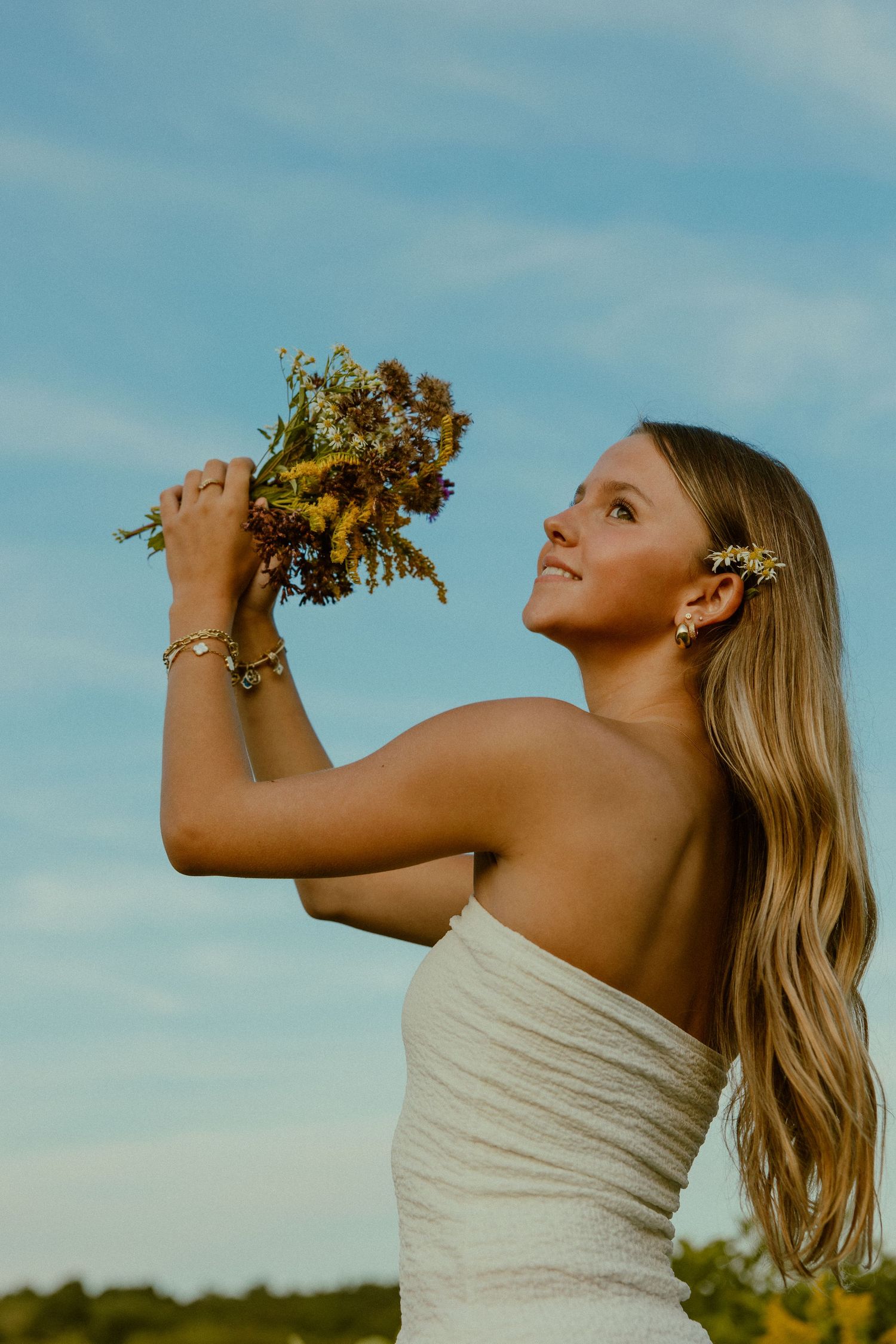 A woman in a white dress poses with flowers against a blue sky in a progressive sequence of artistic shots.