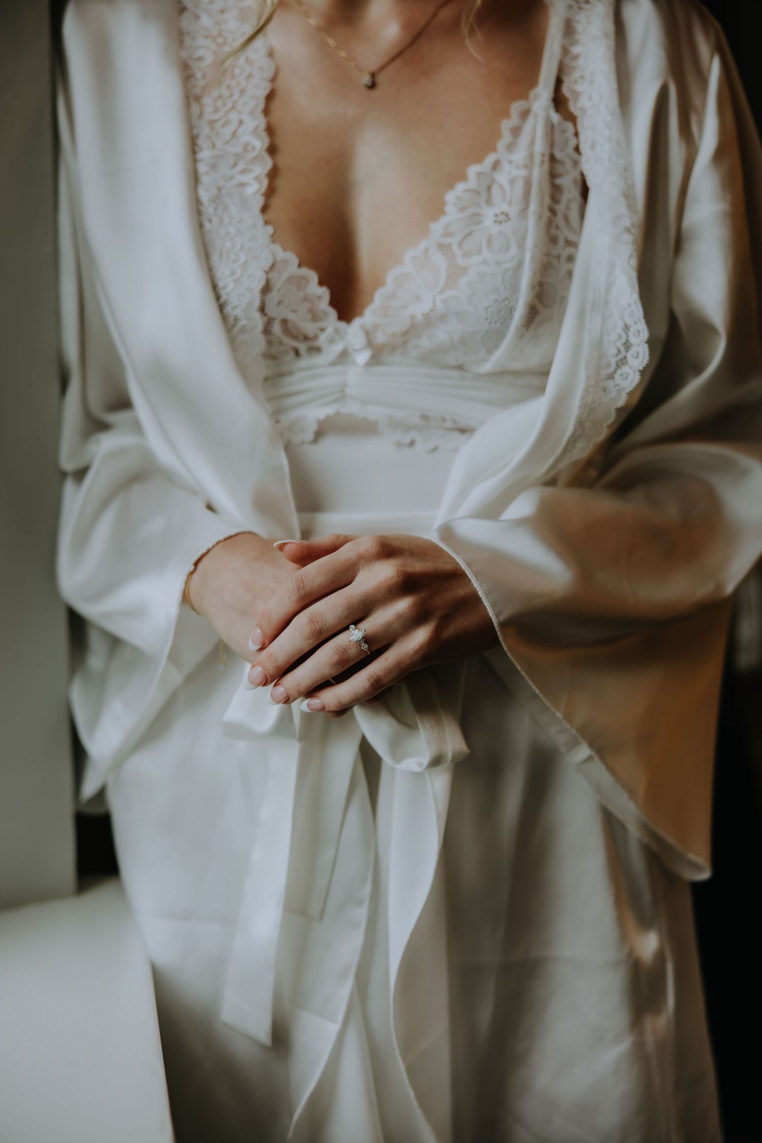 Close-up details of a delicate white lace wedding dress with long sleeves and elegant buttons.
