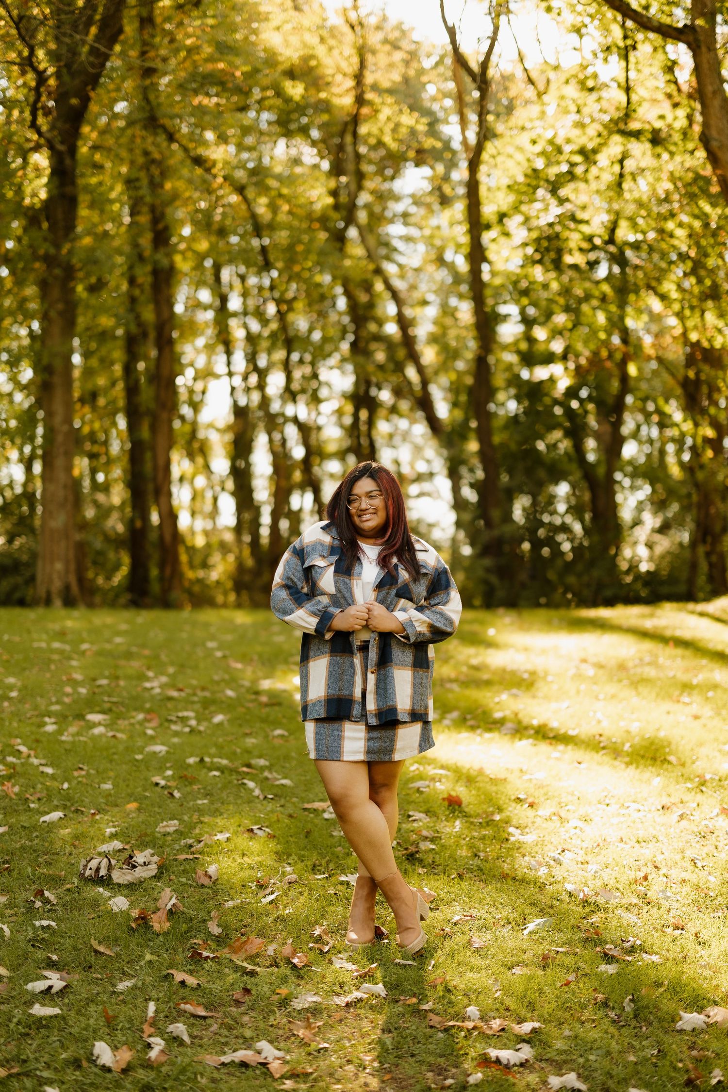 Casual outdoor portrait on a sun-dappled path with golden autumn foliage overhead.