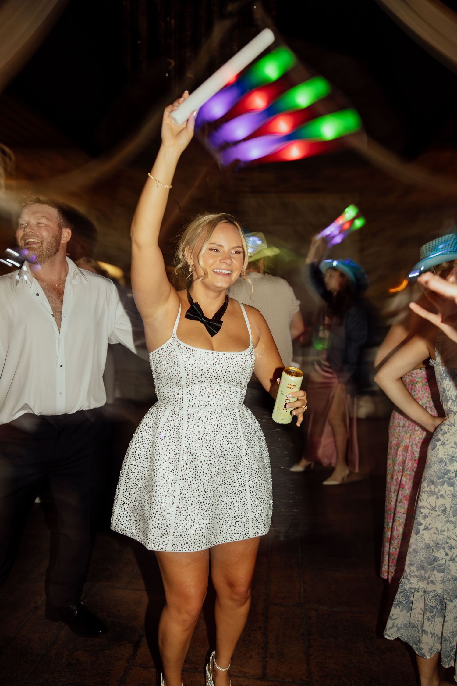 Wedding reception dance party with colorful LED lights illuminating guests dancing and celebrating.