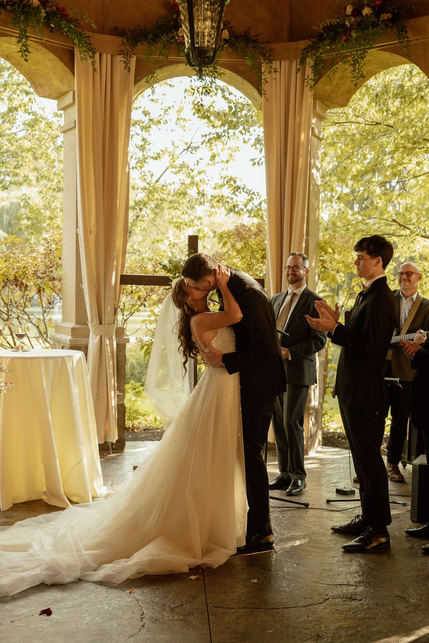 A romantic first dance sequence under an elegant covered pavilion surrounded by wedding guests.
