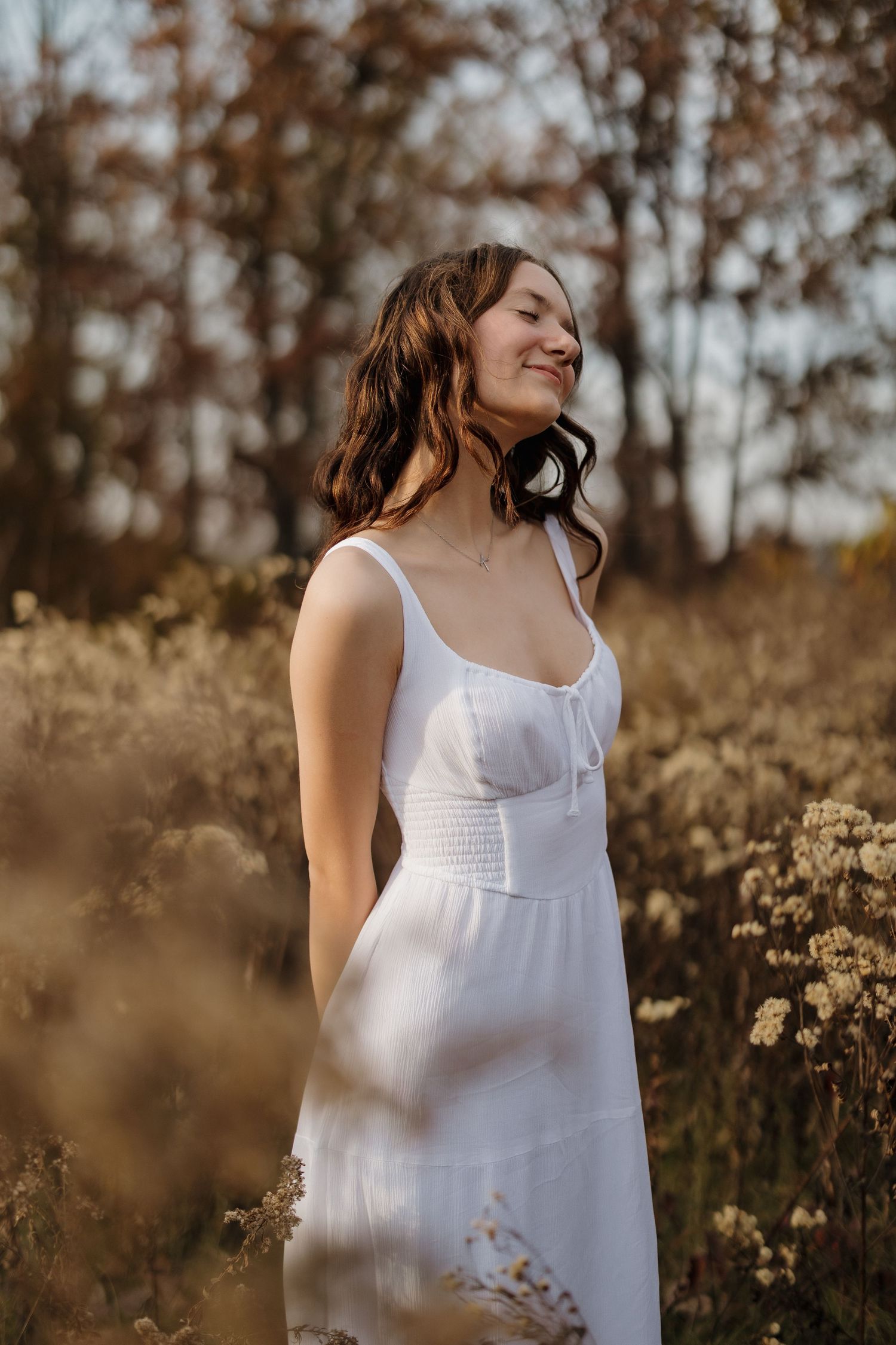 A joyful moment captured in a white dress among tall grass during golden hour.