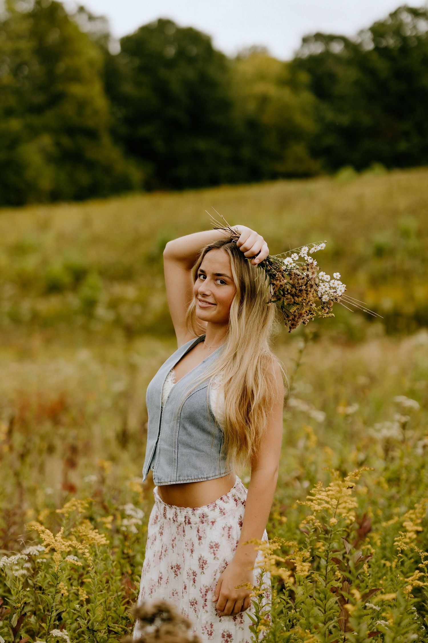 Summer portrait in wildflower meadow with gray crop top and floral skirt outfit.