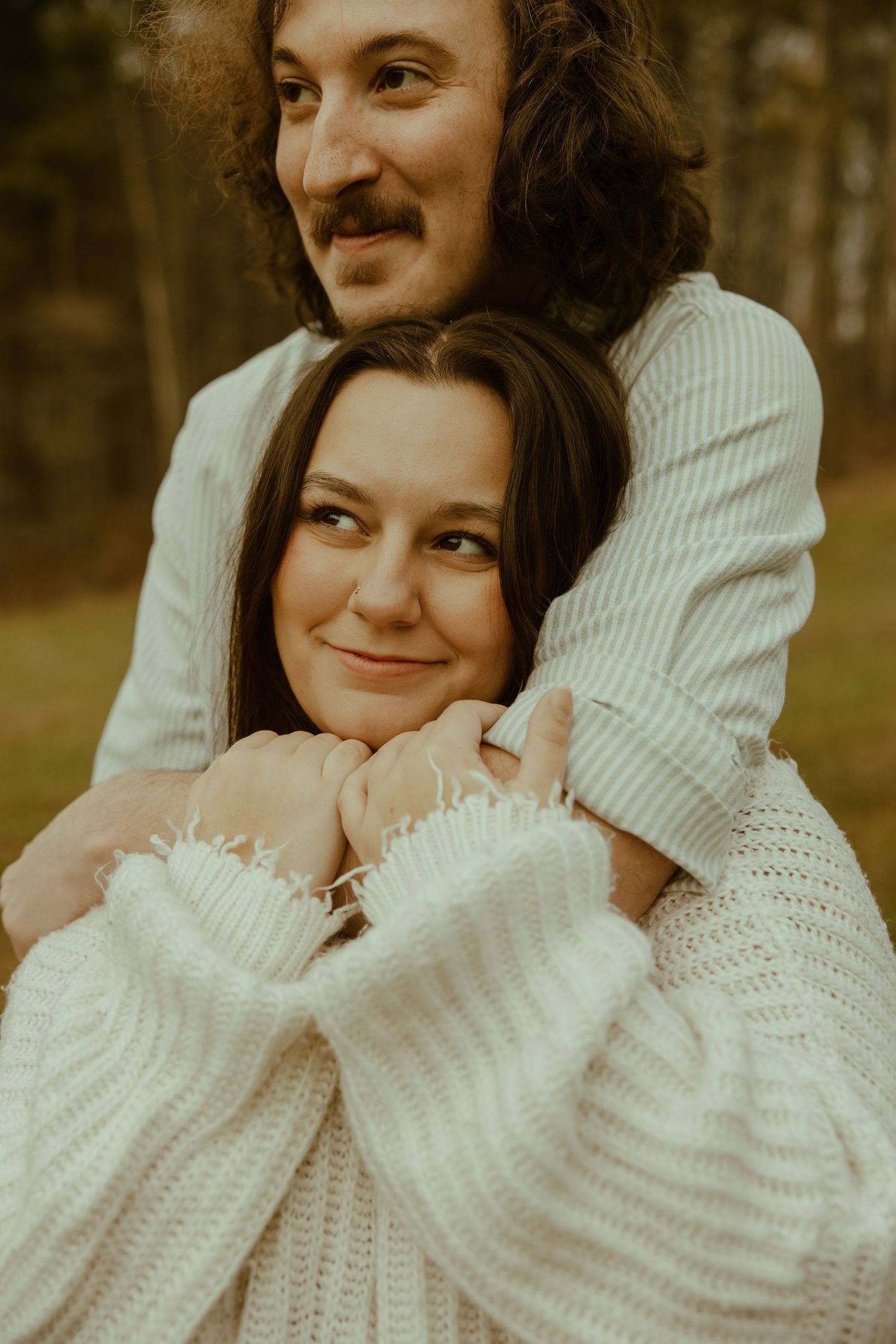 A couple in cozy sweaters share intimate embraces in a series of warm-toned outdoor portrait photos.