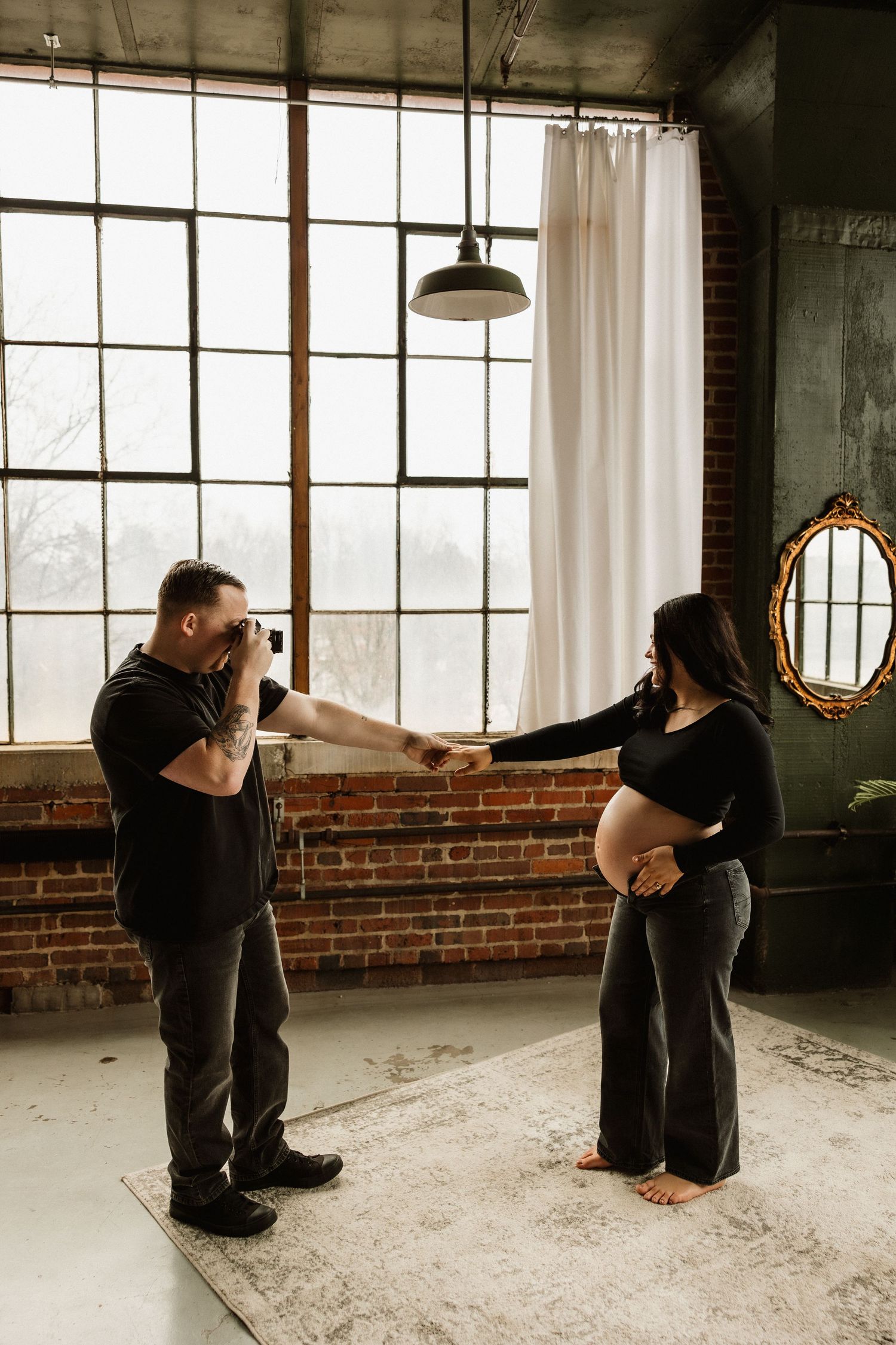 Progressive sequence of yoga or dance poses performed on floor in front of large industrial windows and brick wall.