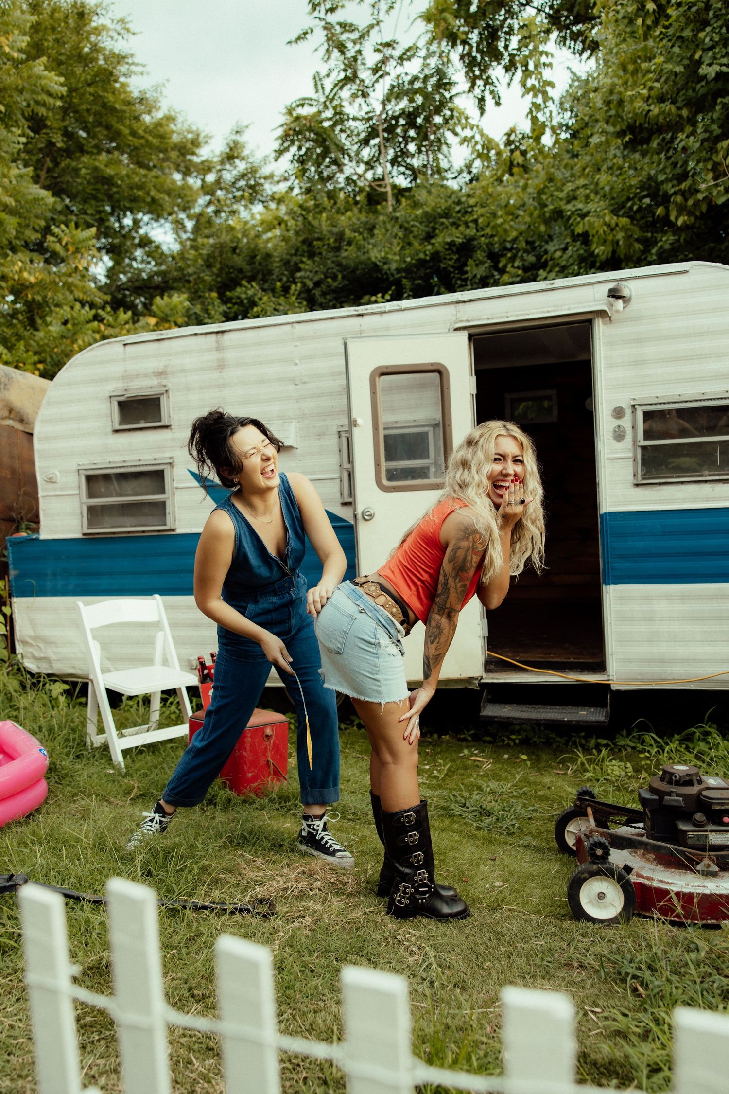 People playing and exercising outdoors near vintage trailers in a grassy area.