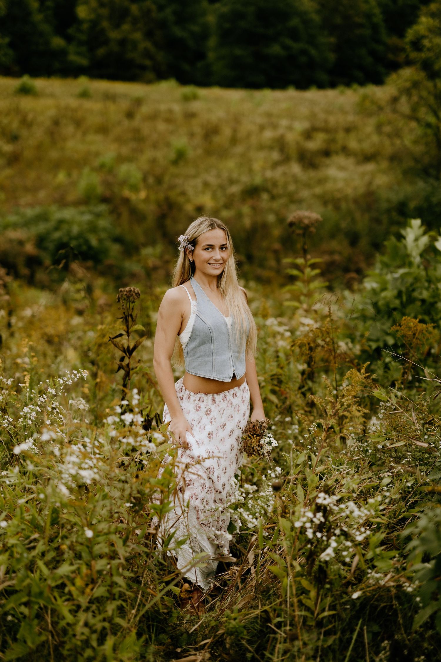 Summer fashion portrait in wildflower field wearing gray top and floral maxi skirt.