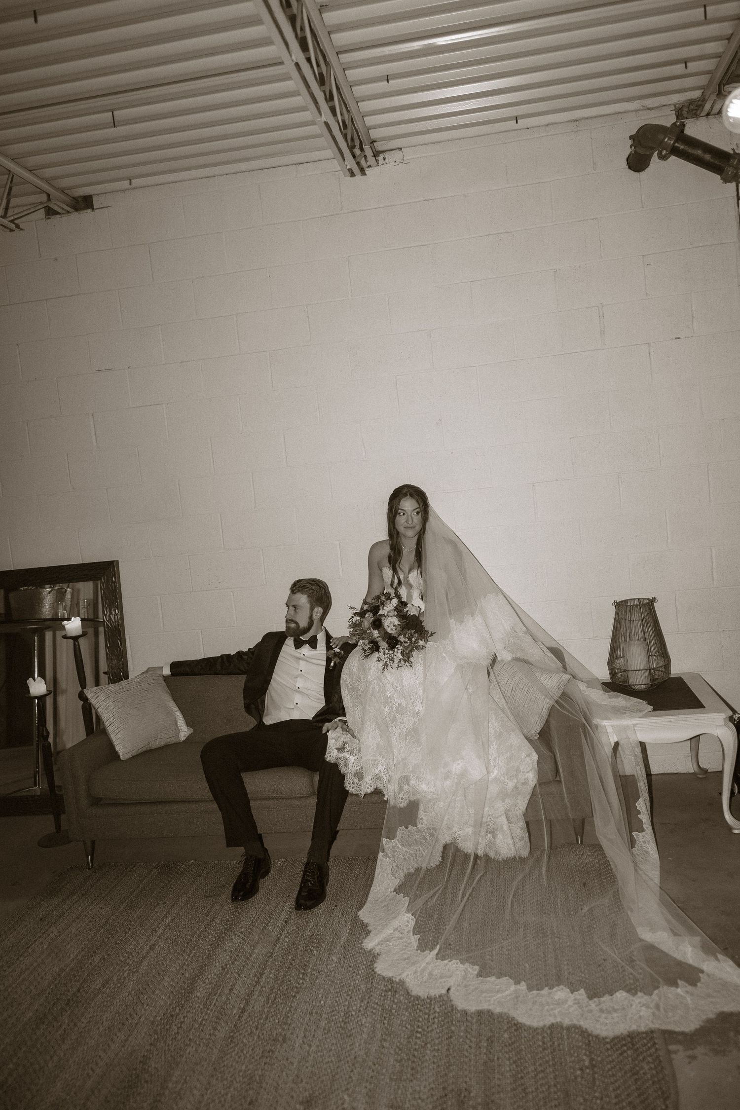 A playful wedding party walking across a hardwood floor with a flowing white wedding dress train.