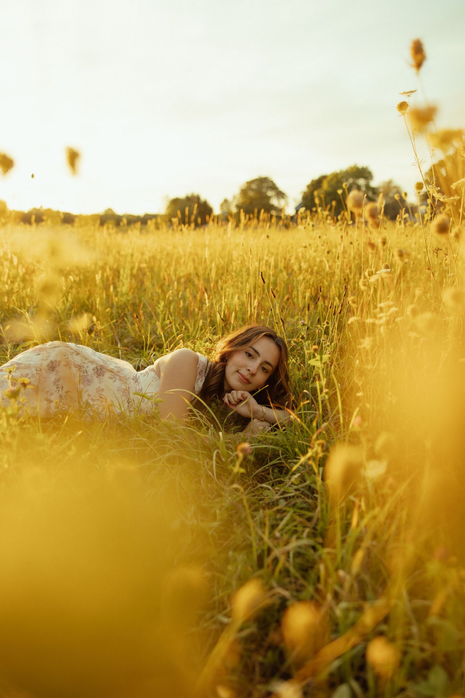 A dreamy golden hour scene in a wildflower meadow with someone lying peacefully among tall grasses at sunset.