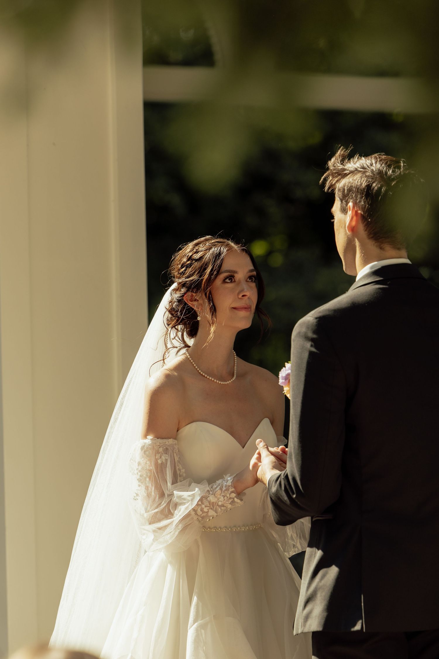 Sunlit wedding ceremony scene with elegant decor and white columns in the background.