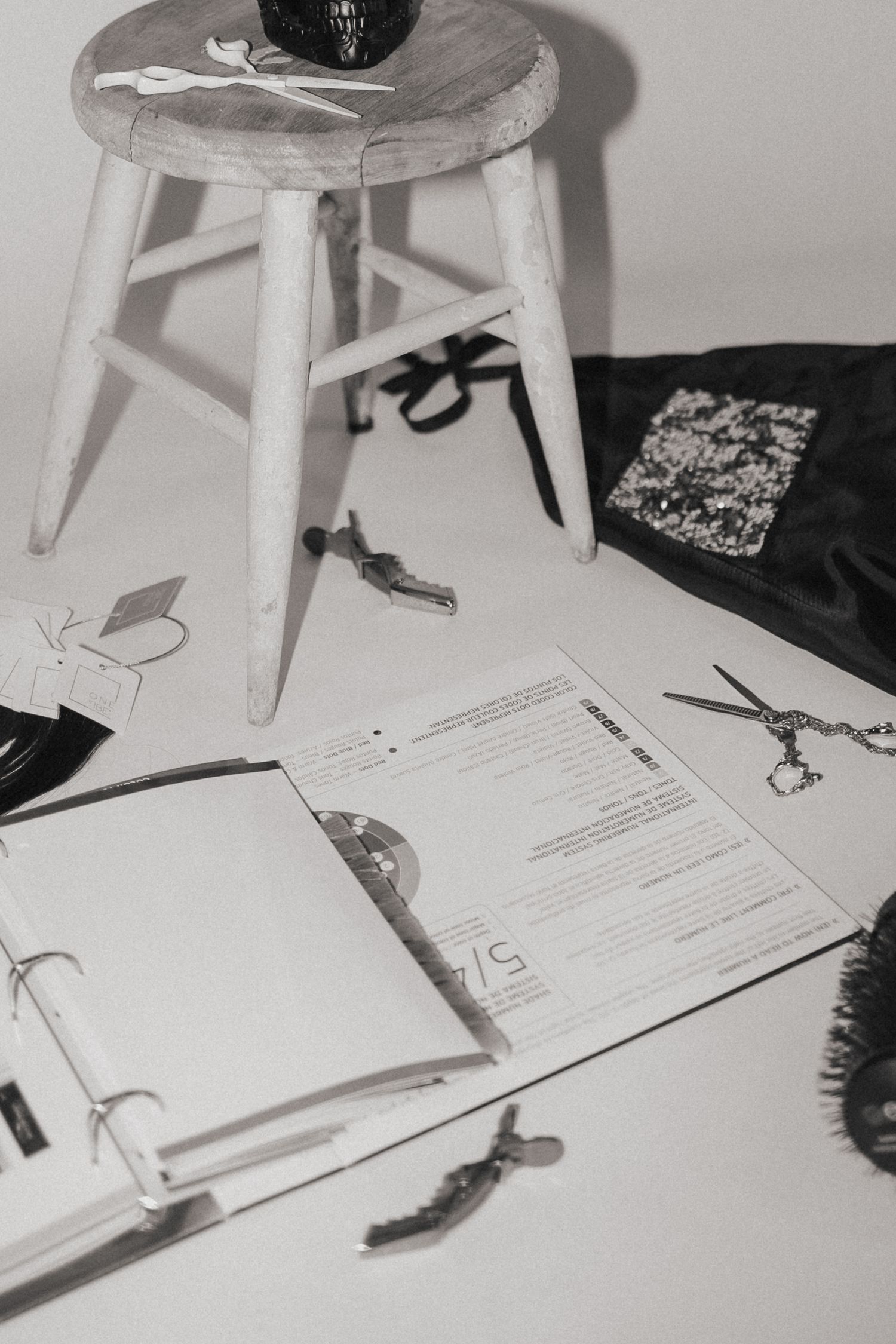 Overhead view of white stool with styling tools and paperwork scattered below.