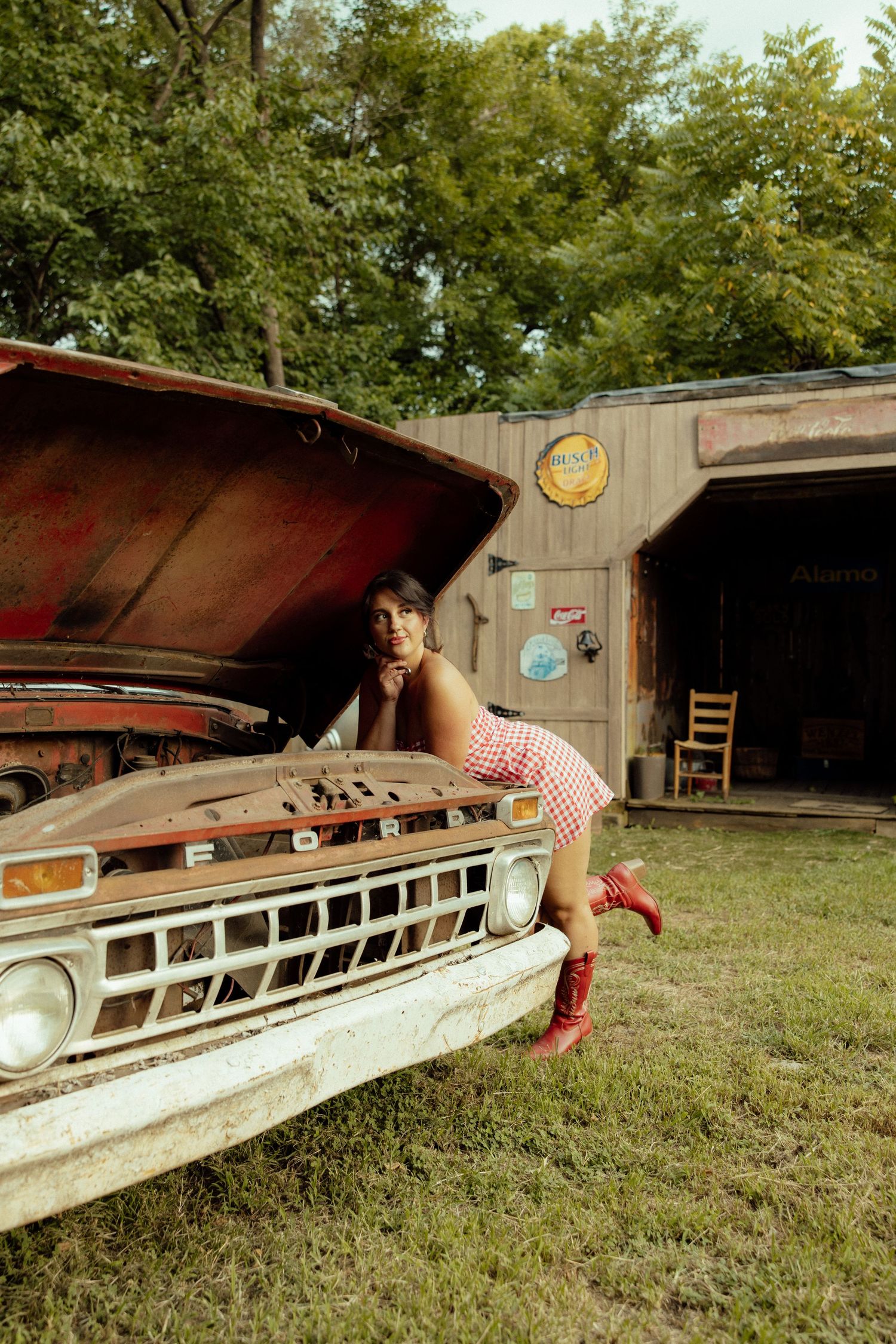 A sequence of photos showing a person lying down and sliding under a vintage wooden boat hull in a backyard setting.