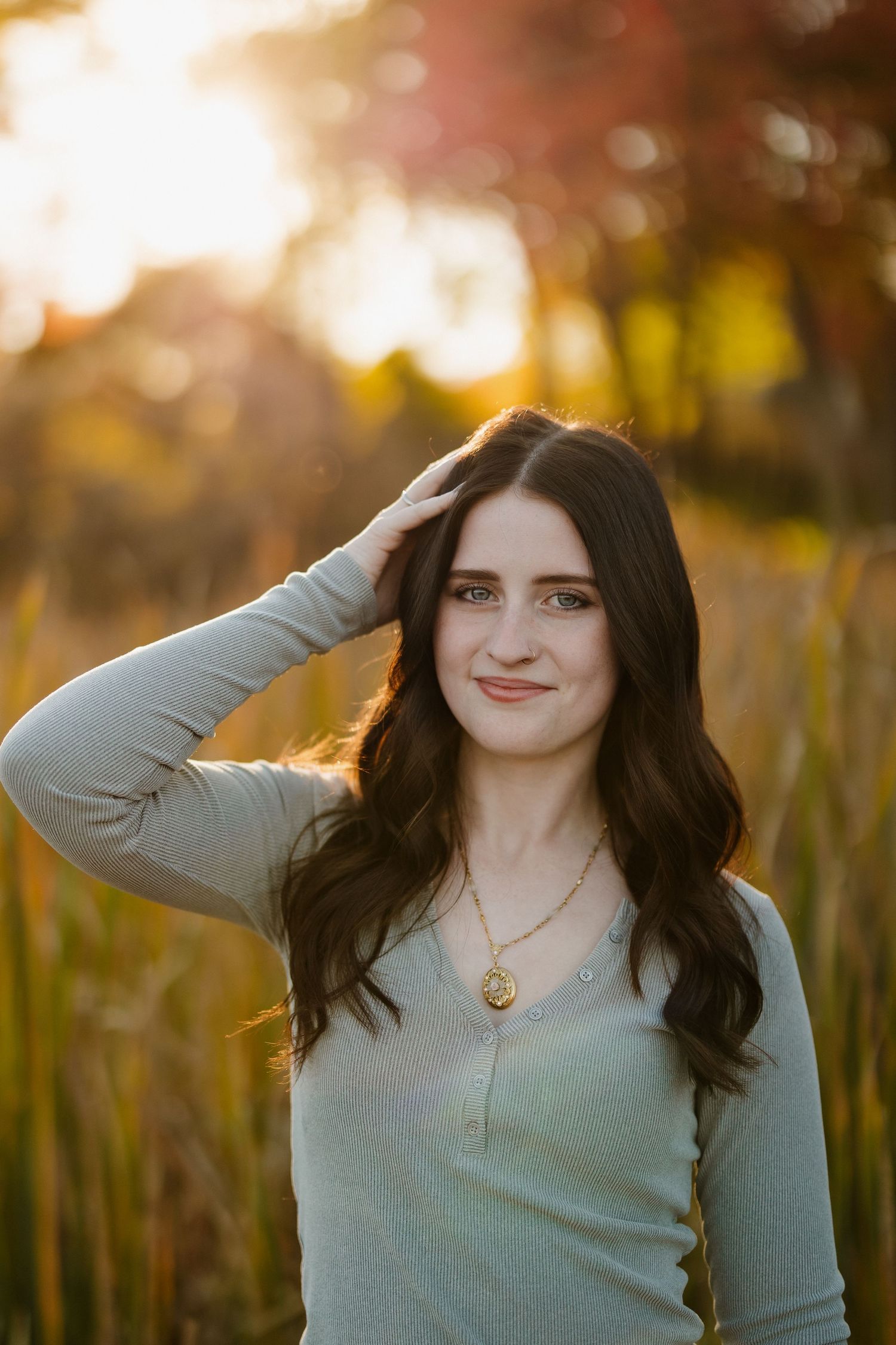 Portrait in gray sweater with sun flare and autumn colors in background.