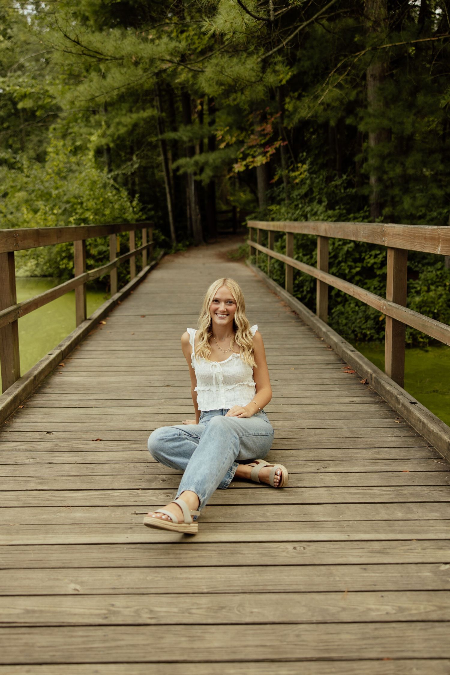 A sequence of photos showing someone sitting and lying on a wooden bridge walkway surrounded by green forest.