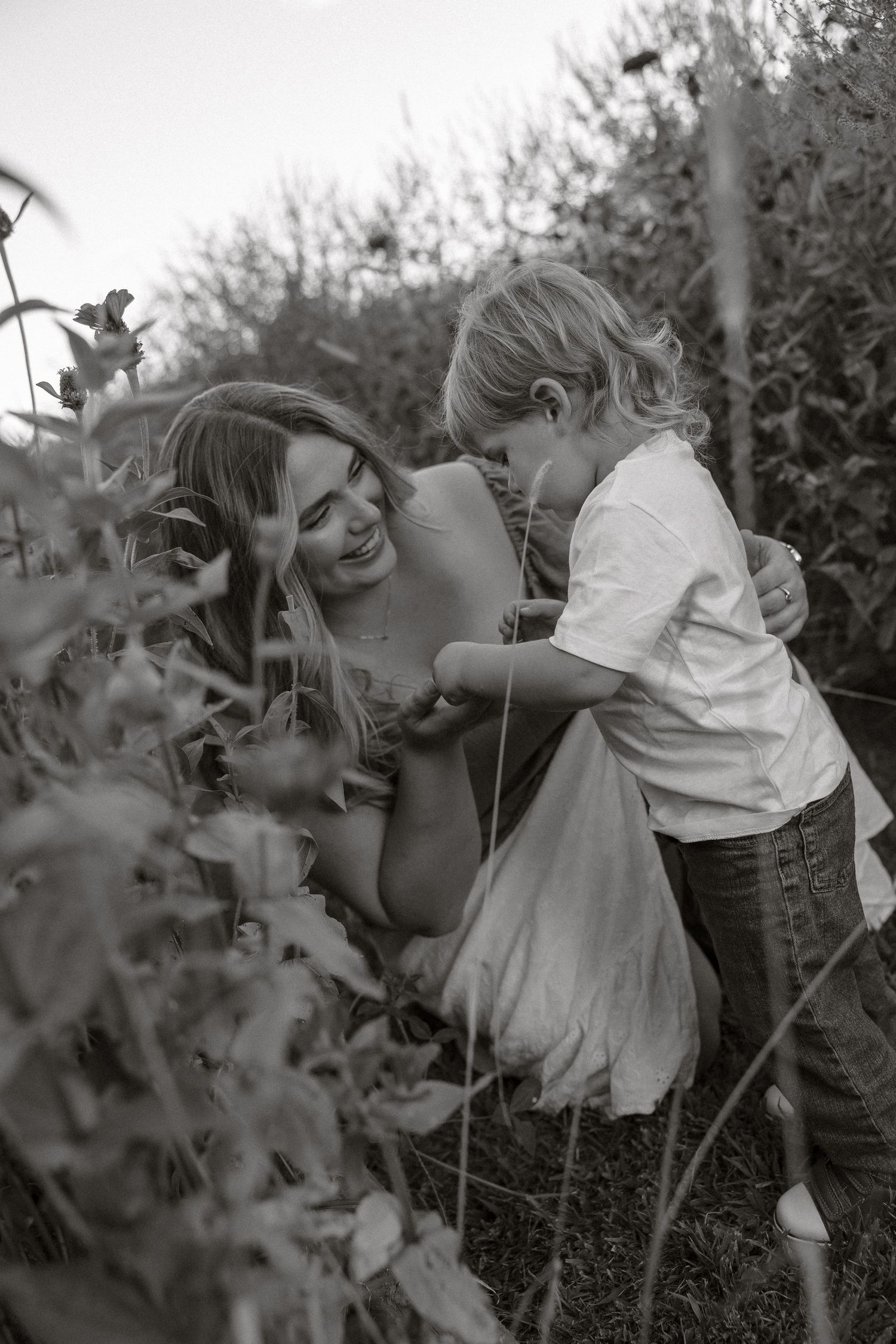 A black and white photo series shows playful moments between two people in a garden setting.