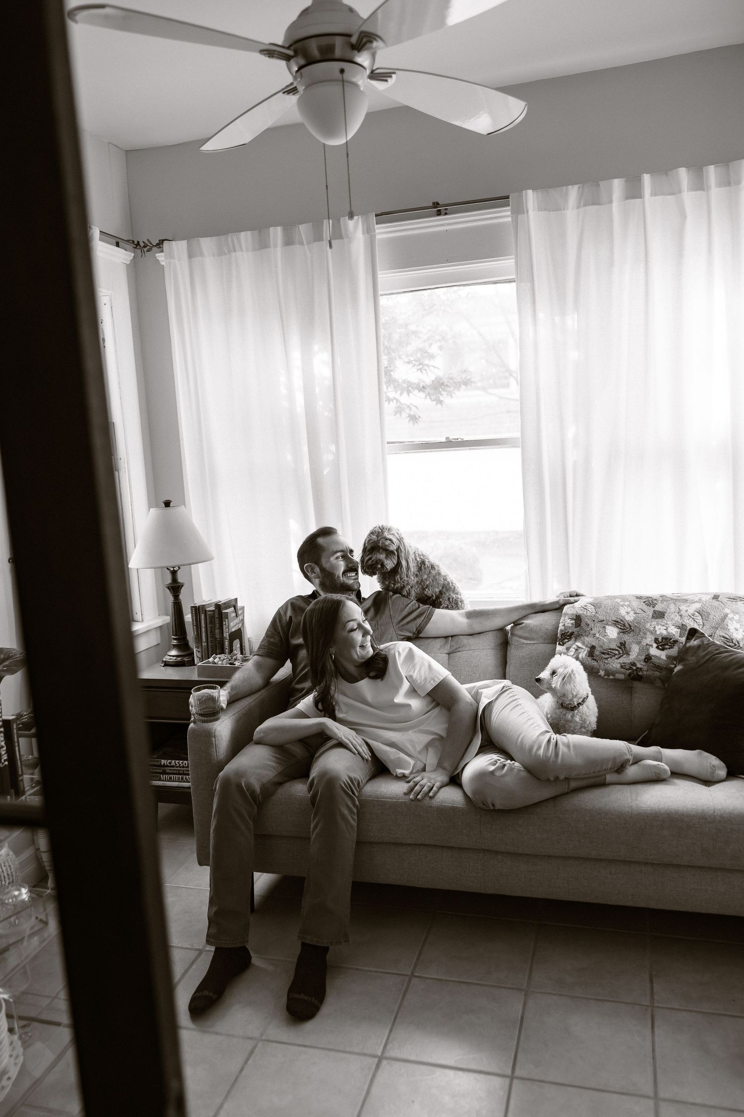 A series of black and white photos showing someone relaxing on a couch in a sunlit room with white curtains.