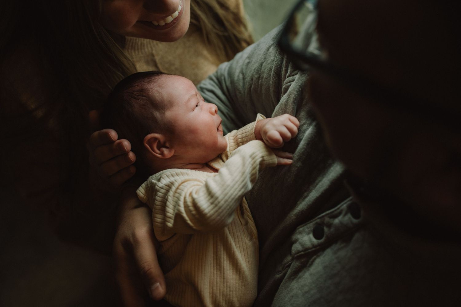 A softly lit moment showing a baby nestled against someone in warm lighting.