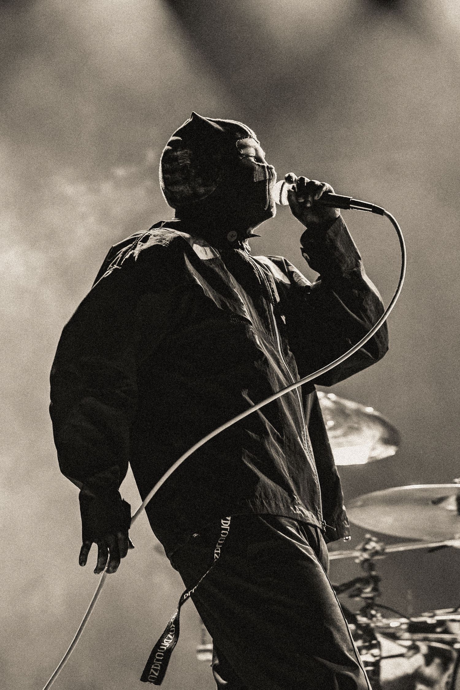 Black and white profile shot of performer singing into microphone on stage.
