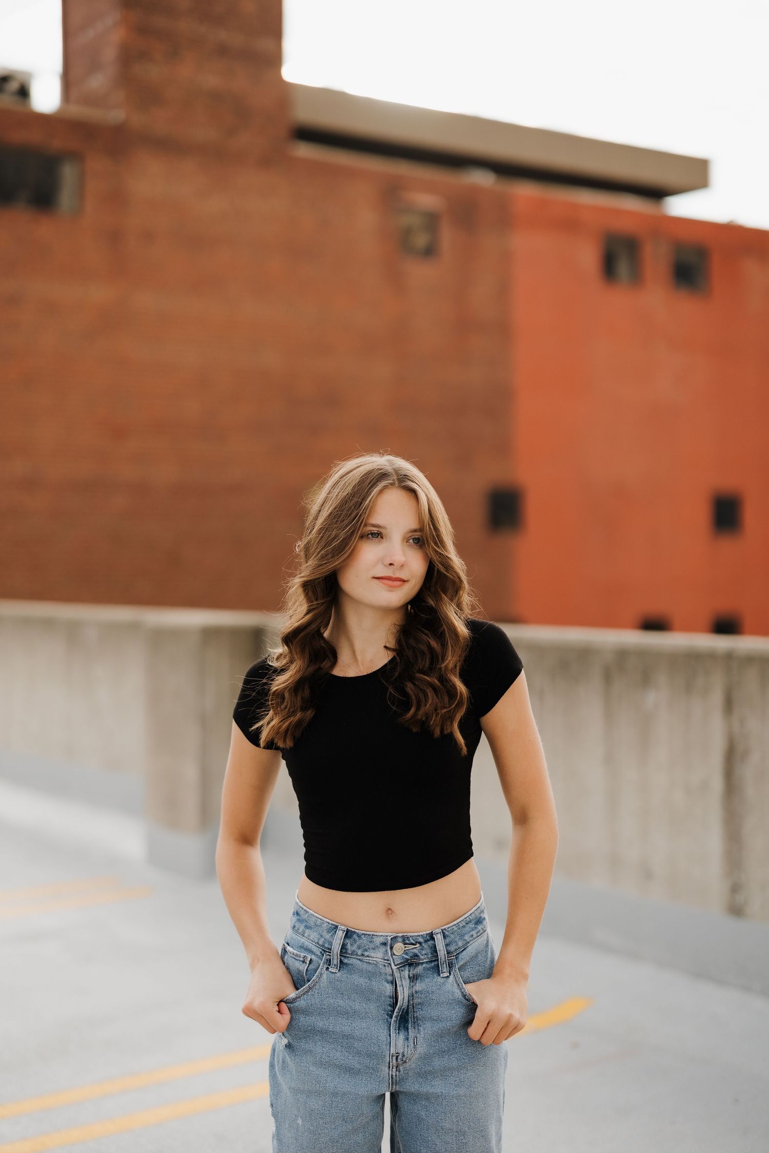 Modern urban portrait featuring casual streetwear against an industrial brick building backdrop.