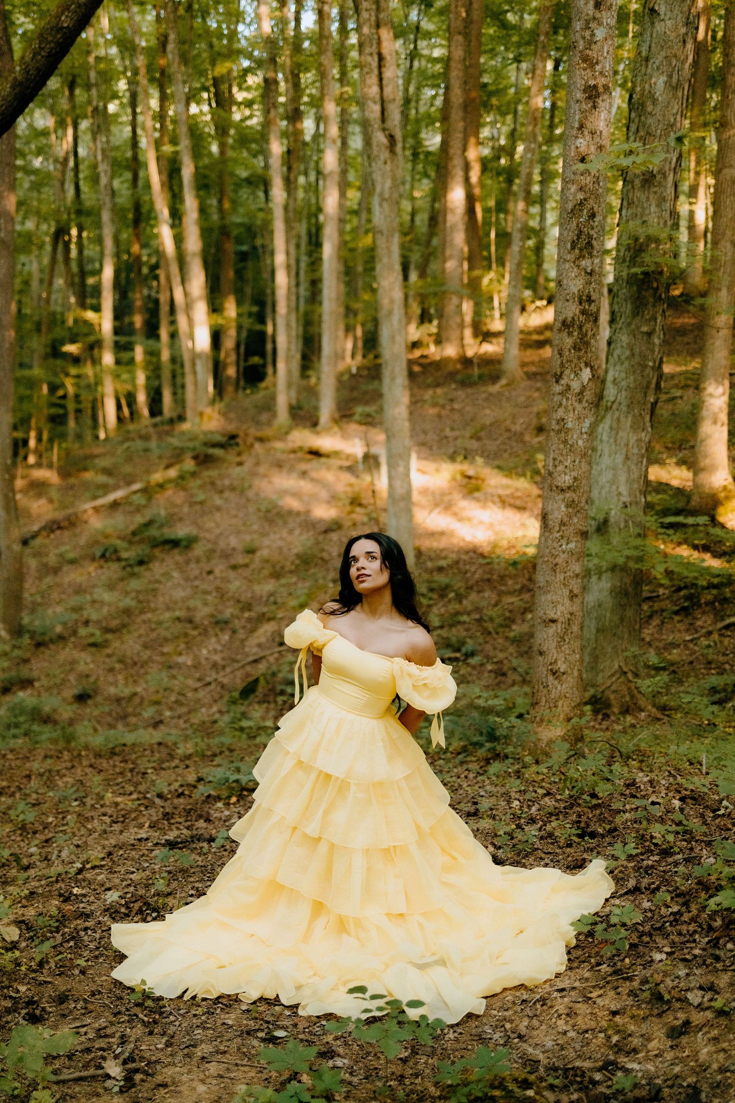 Elegant yellow ballgown photoshoot in sunlit forest setting.