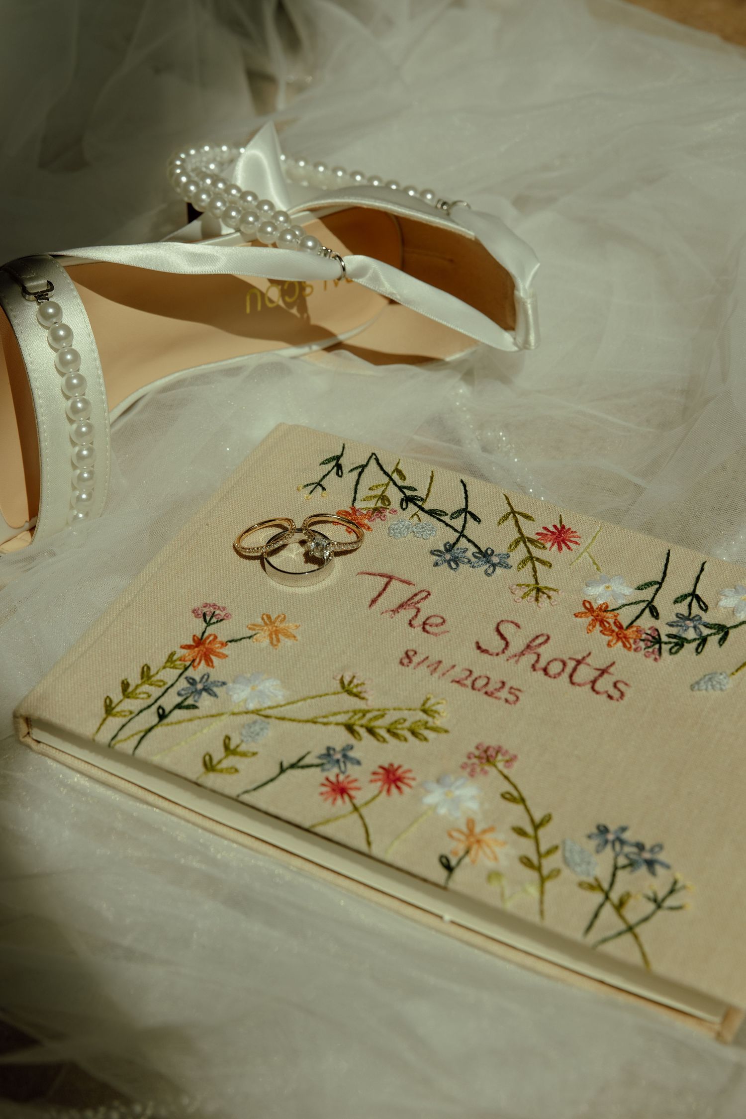 Delicate embroidered floral designs decorate cream-colored fabric with text details.
