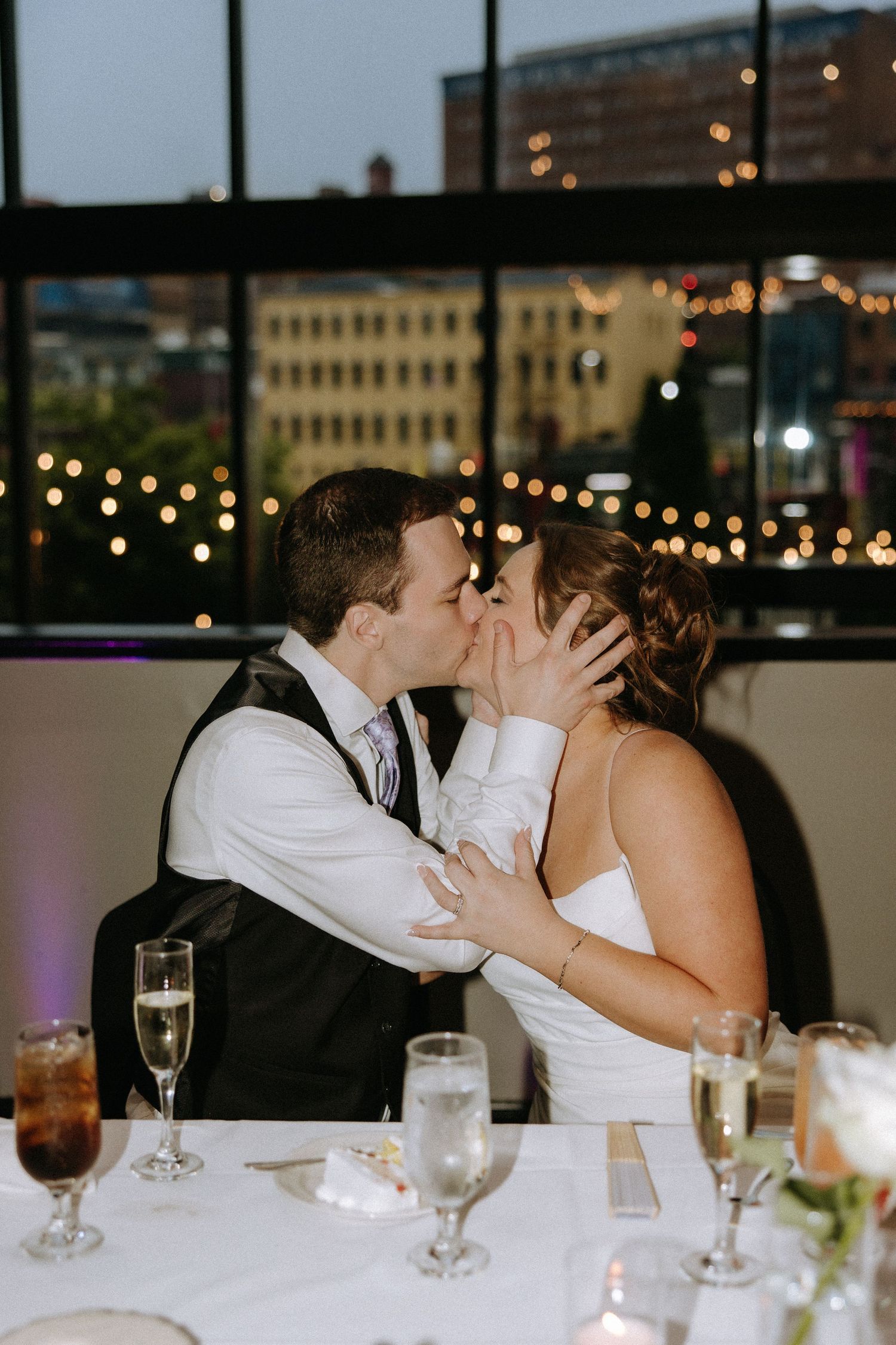 Wedding reception dinner scene with romantic lighting and city views.