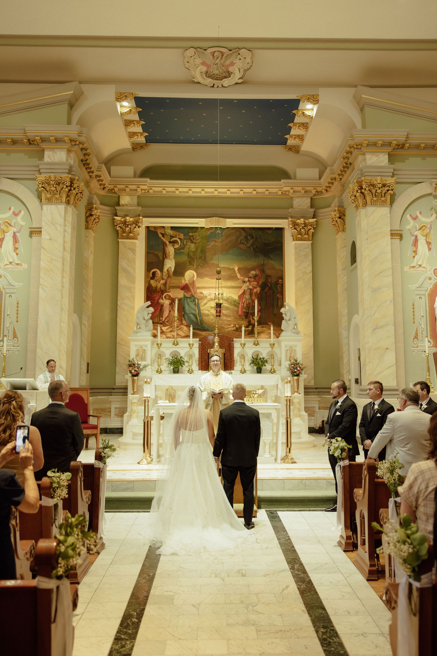 Elegant church wedding ceremony in progress with ornate gold decor and white marble columns.