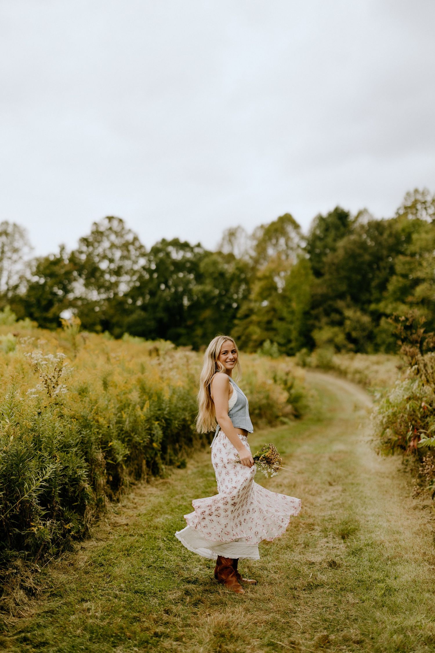 Dancing along a winding country path in floral dress during golden hour.