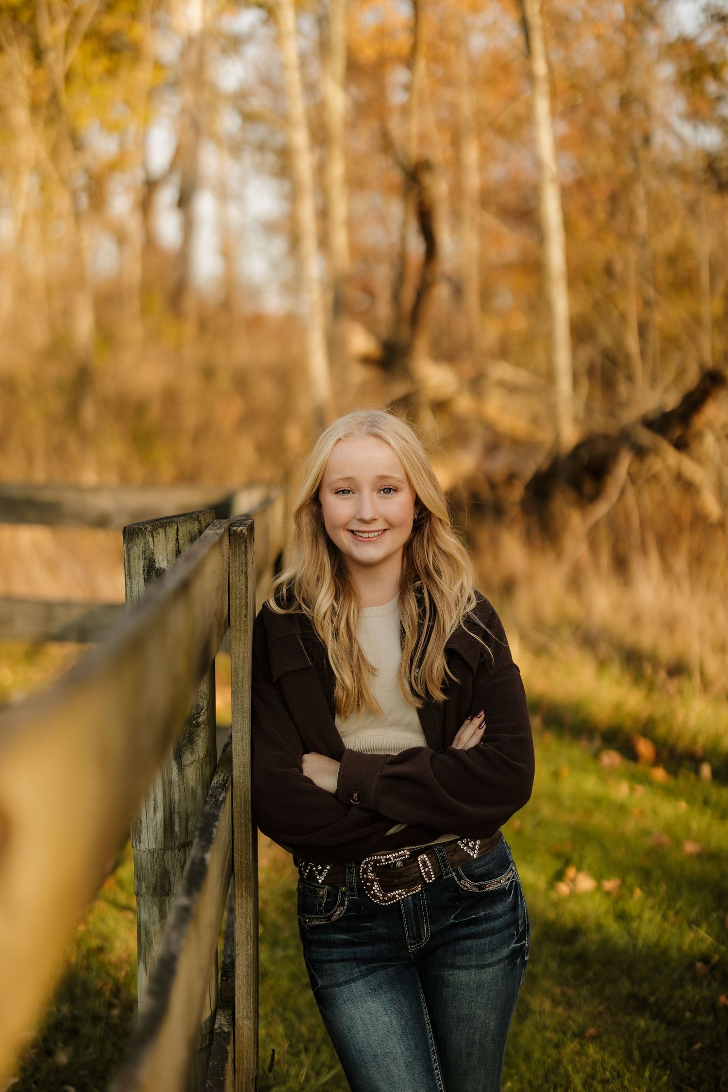 A casual country portrait of someone leaning against a wooden fence during golden hour.