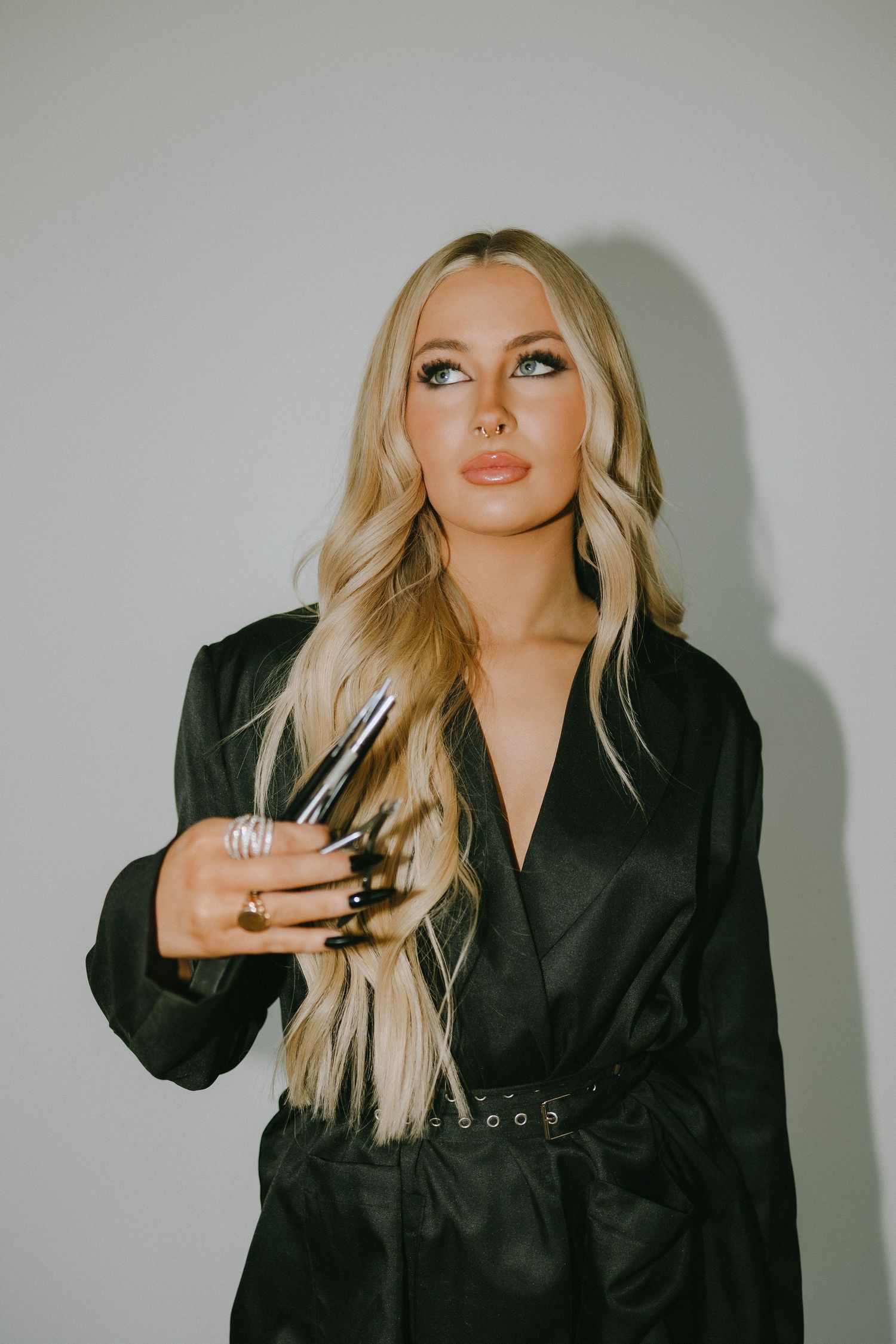 Studio beauty shot featuring black belted dress and statement jewelry.