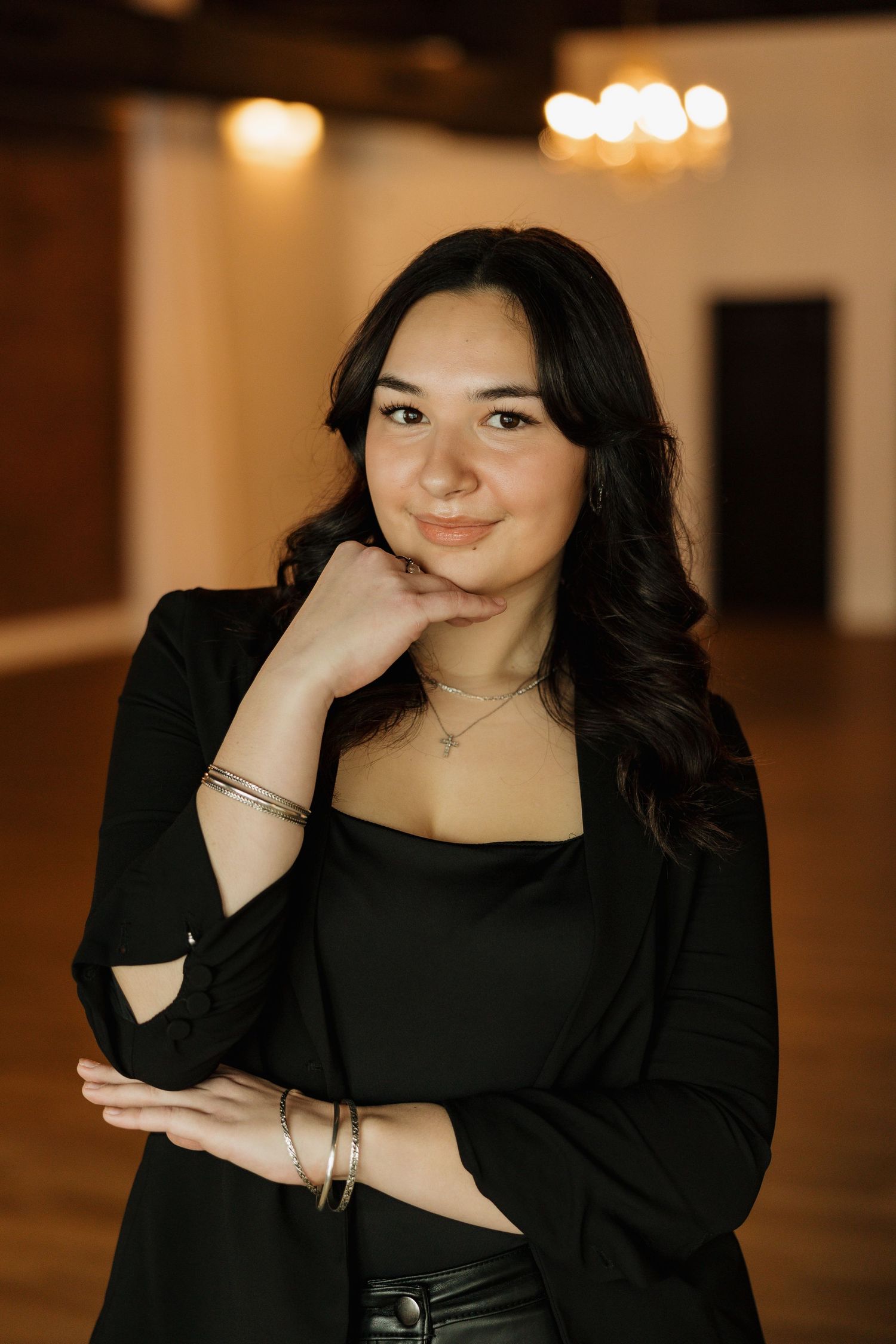 Professional studio portrait in black attire with soft lighting and a casual pose.
