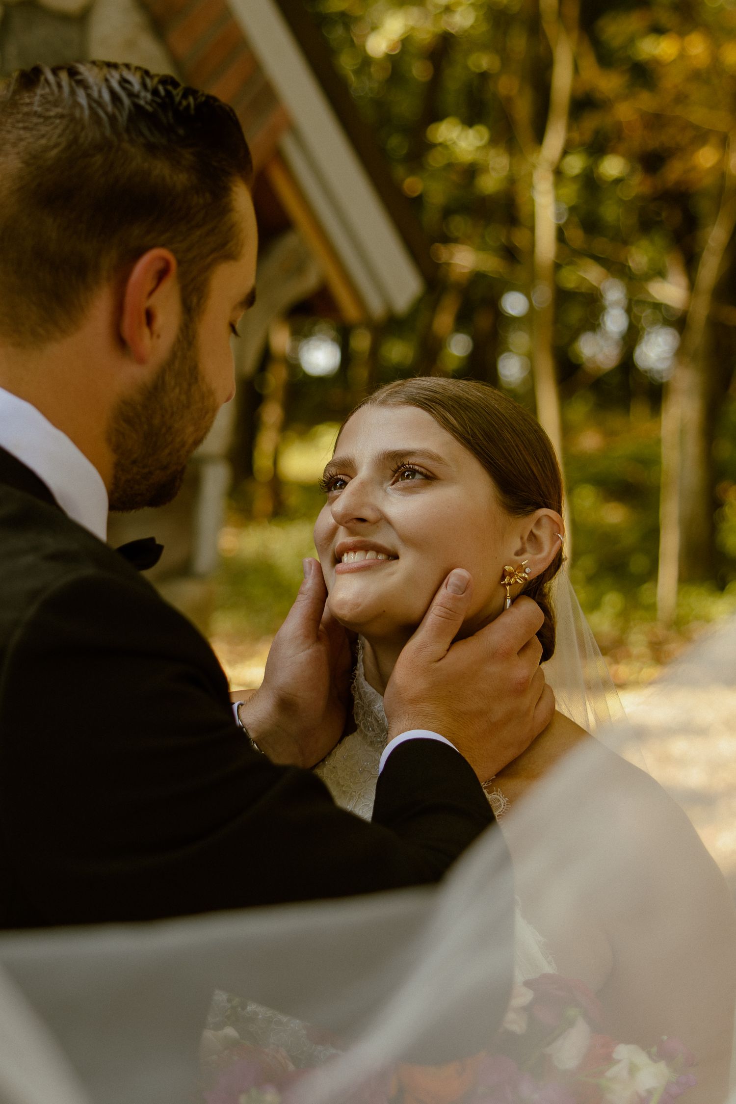 Romantic couple shares an intimate moment during sunset in a wooded outdoor setting.