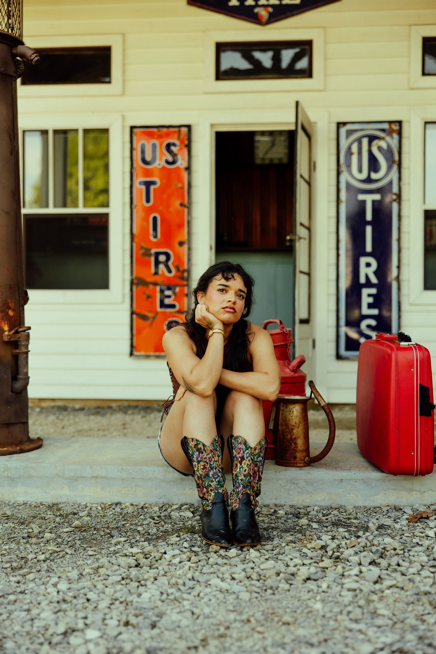 Vintage scene at old US Tire store with retro signs and red suitcase.