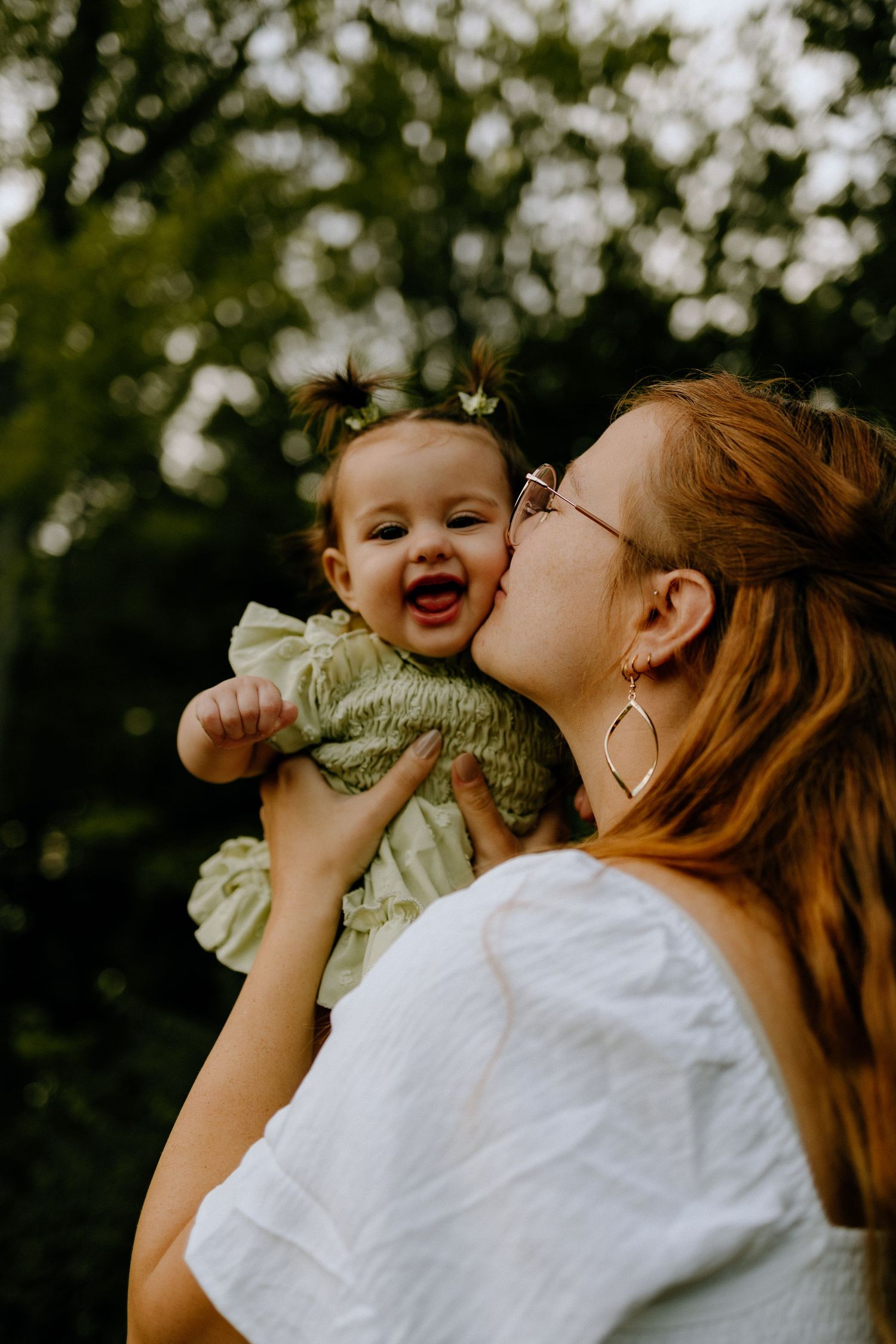 Joyful moment between parent and baby against blurred green background.