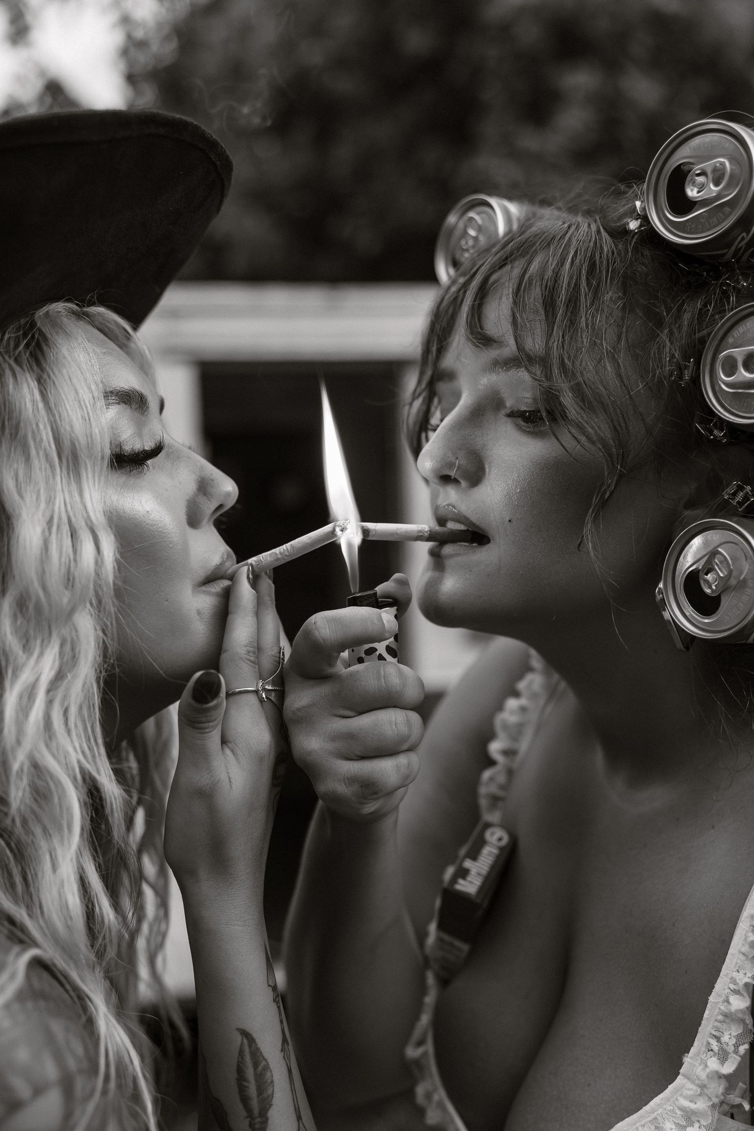 Two people share an intimate moment while blowing smoke rings in black and white artistic photography.